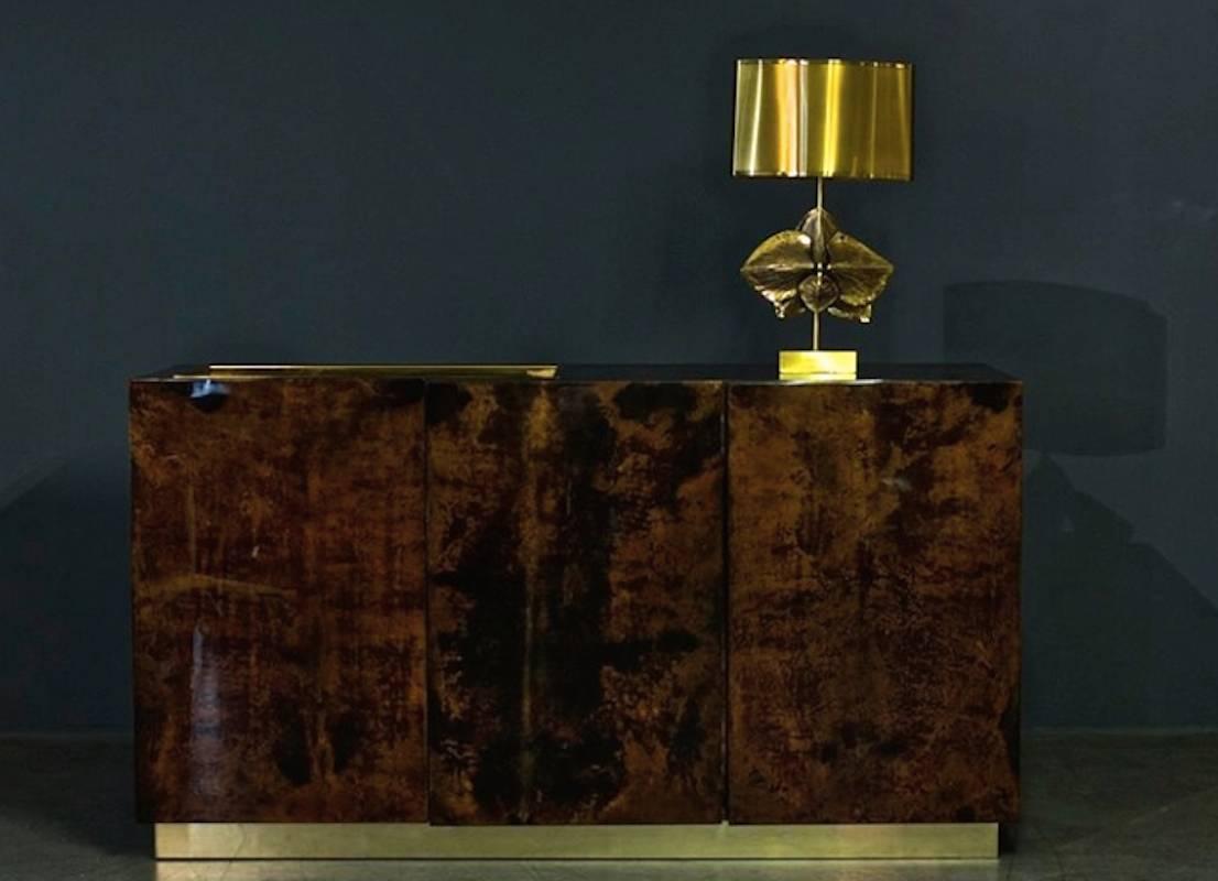 Lacquered goatskin sideboard on brass base, designed by Aldo Tura, circa 1970. Glass shelf and a brass bar on top.