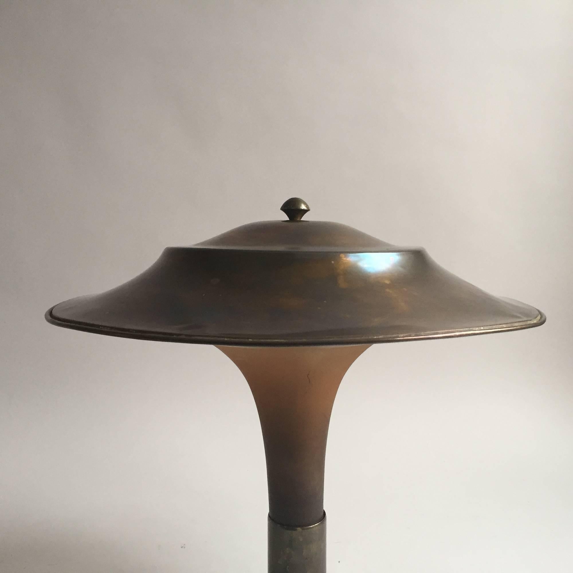 Fog & Mørup Fakkellampen

Very Rare Danish 30Th Art Deco Table Lamp from Fog & Mørup, Denmark. The Foot and the Shade are out of bronze patinated Brass. Matt colored stained glass stem.  Very nice Light. Full functional with new black fabric cable