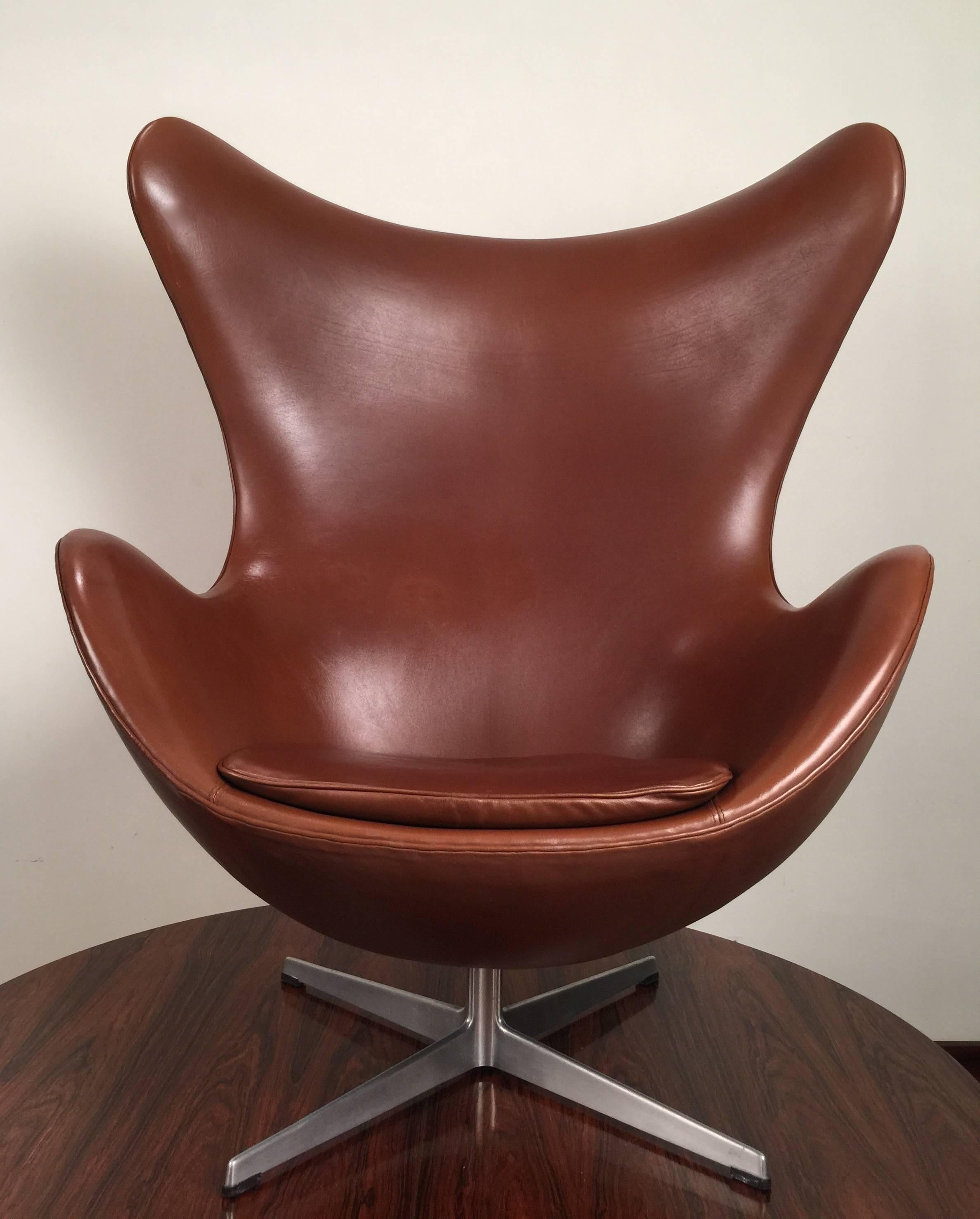 An early brown leather egg chair designed by Arne Jacobsen and produced in 1967 by Fritz Hansen on a four star aluminium swivel base. The chair retains its original brown leather and a lovely patina from age and use. Unlike contemporary egg chairs,