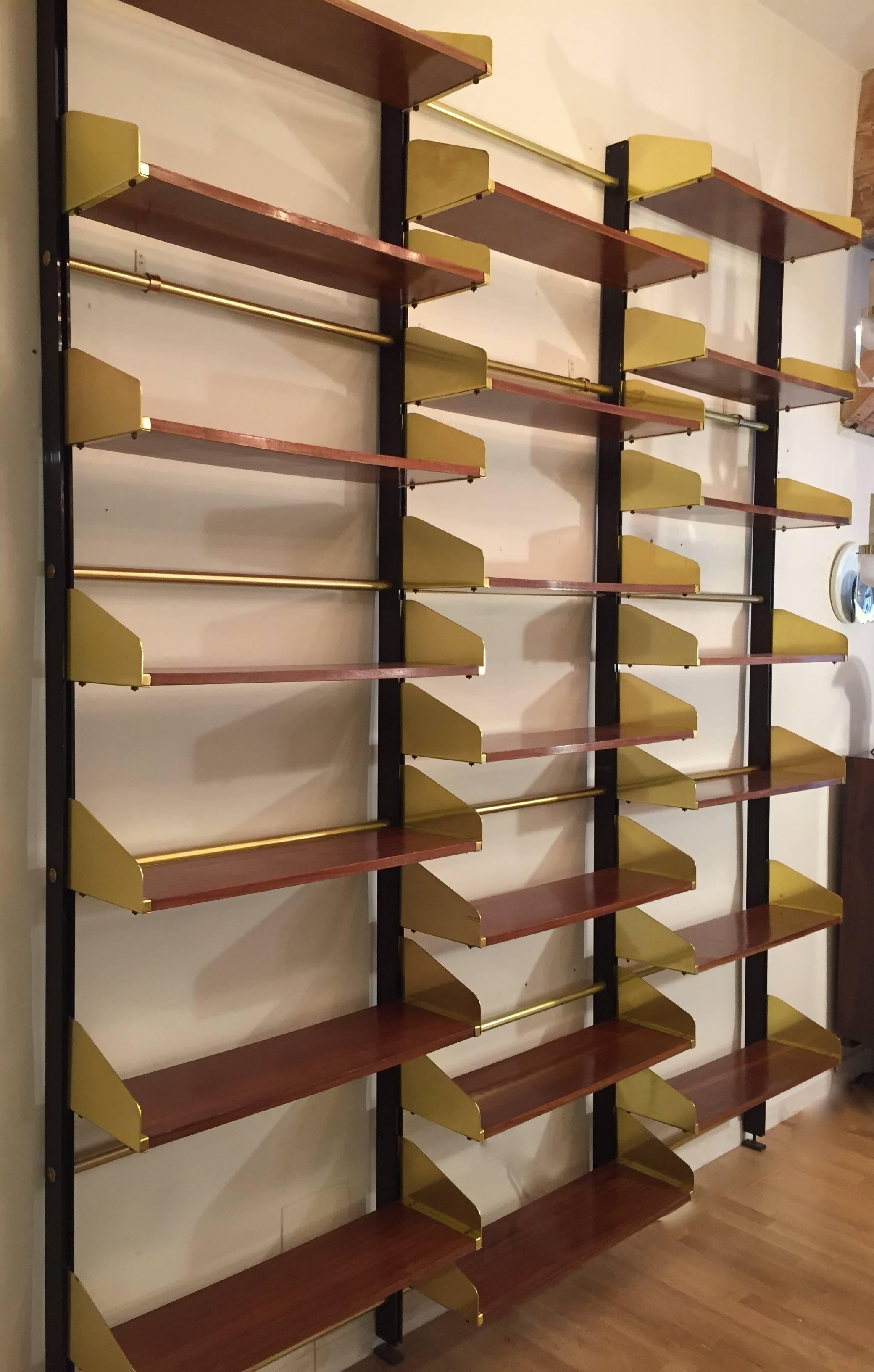 An Italian 1950s bookcase; brass anodized aluminum uprights and brass rods; shelves in plymouth veneered mahogany. Adjusted rack system. Beautiful minimalistic design. Excellent condition.