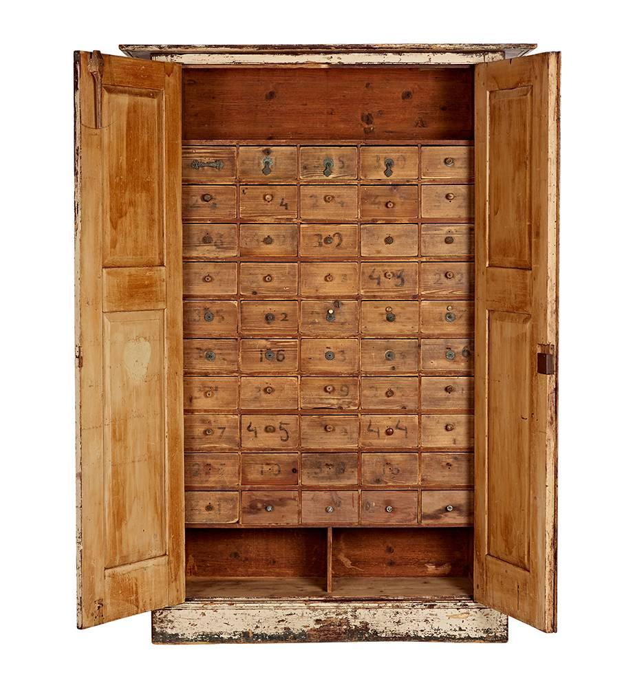 With remarkable patina, this white-painted oak cabinet was salvaged from a quincaillerie, a French hardware store! Behind the enormous paneled doors there are 50 small drawers, where fasteners and parts were kept for more than 100 years.

Measure:
