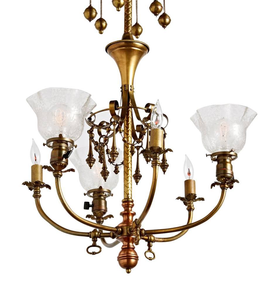 There are so many incredible elements on this chandelier, from the original two-tone brass and copper finish, to the decorative, dangling ornaments, to the ruffled and etched shades; this is a rare and impactful fixture. Companies like Beardslee