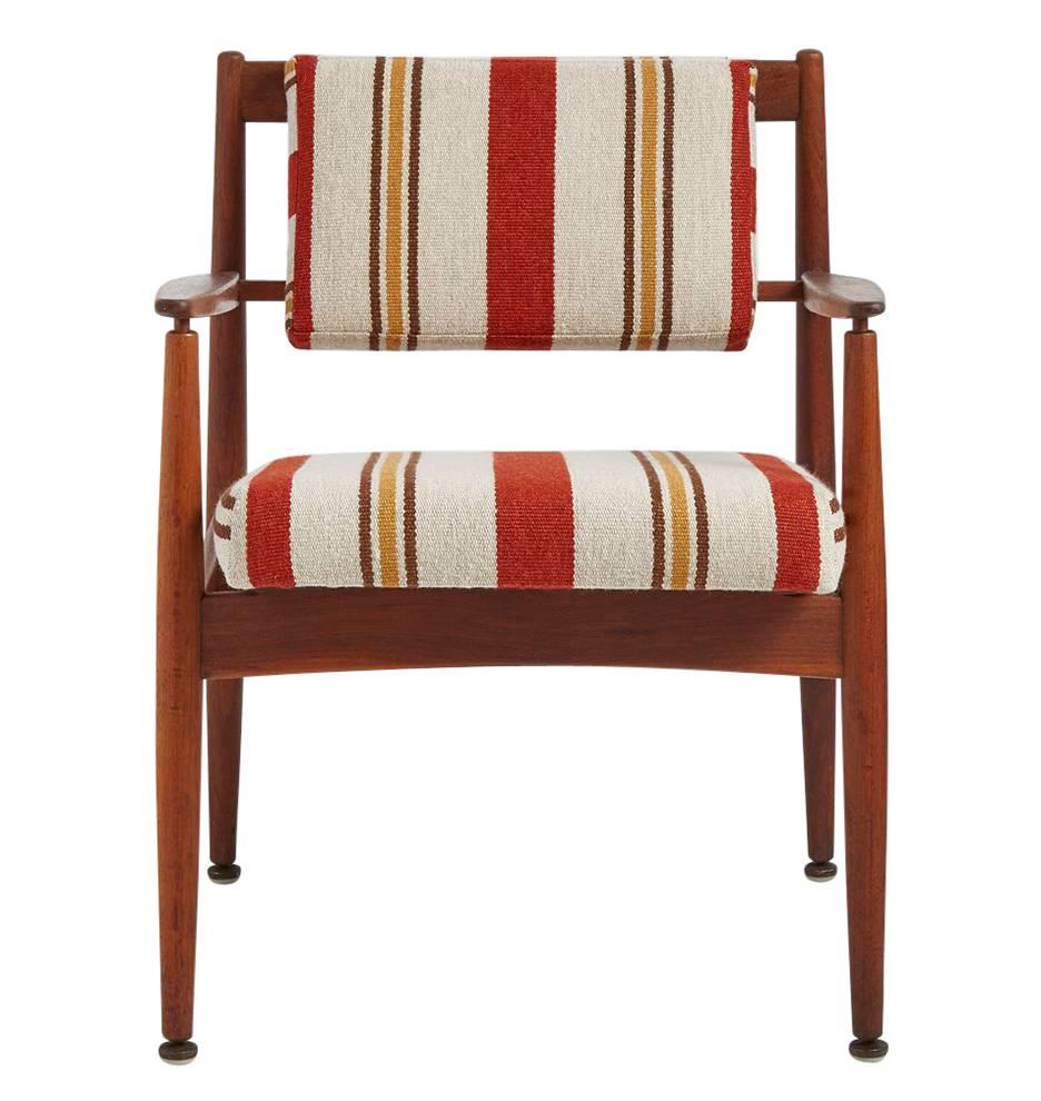Designed by Jens Risom as Model C160, this armchair features some of Risom's characteristic forms and materials. Made from turned walnut, this chair has been completely restored with striped, woven fabric cushions. While the autumn-toned fabric is