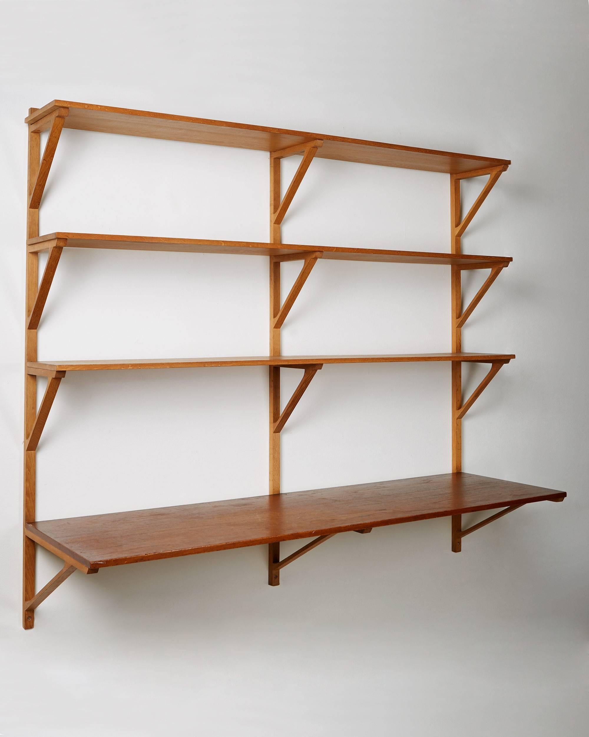 Book shelves designed by Börge Mogensen for Erhard Rasmussen,
Denmark, 1950s.
Oak and teak.
Measures:
H 136 cm/ 4' 5 1/2''
W 154 cm/ 5' 1/2''
Depth of the upper shelves 24 cm/ 9 1/2''
Depth of the Writing shelf 46 cm/ 18''.
 