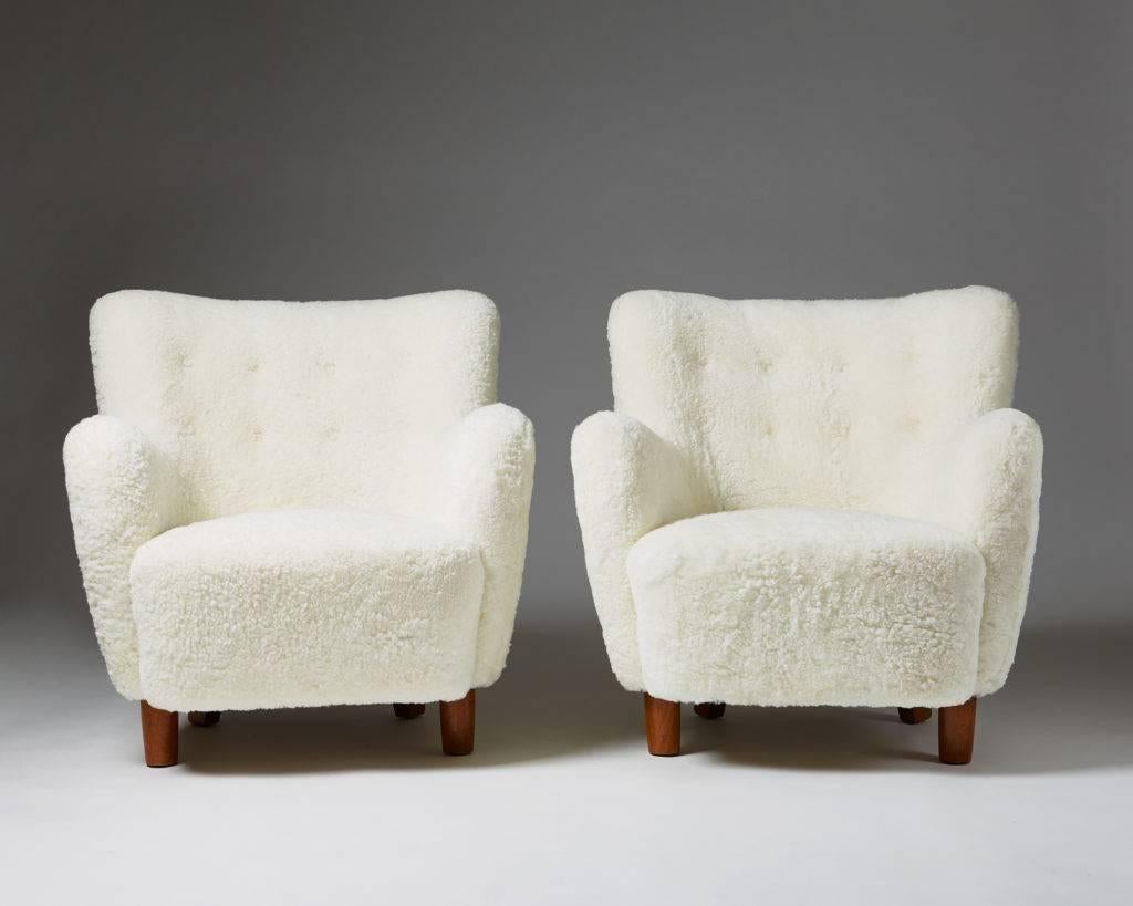 Pair of armchairs, anonymous, 
Denmark, 1940s.

Oak legs and white sheepskin upholstery. 
Measures:
H: 83 cm/ 2' 9 1/8''
W: 80 cm/ 2' 8''
D: 83 cm/ 2' 9 1/8''
SH: 43 cm/ 16 7/8''.

This is a very comfortable piece to sit on. The sheep skin