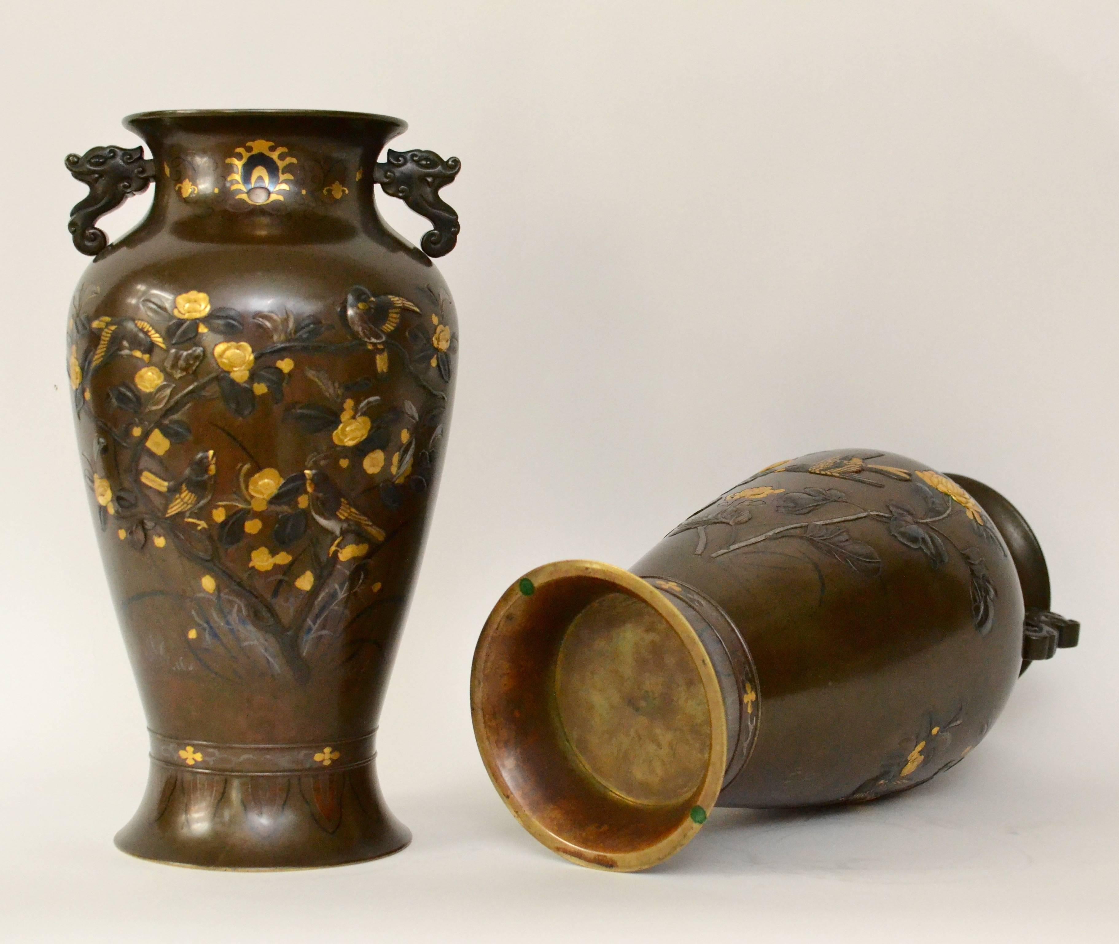 A pair of mixed metal vases, Meiji period (1868-1911). Each chiselled and inlaid in high and low relief with birds among flowers and trees.