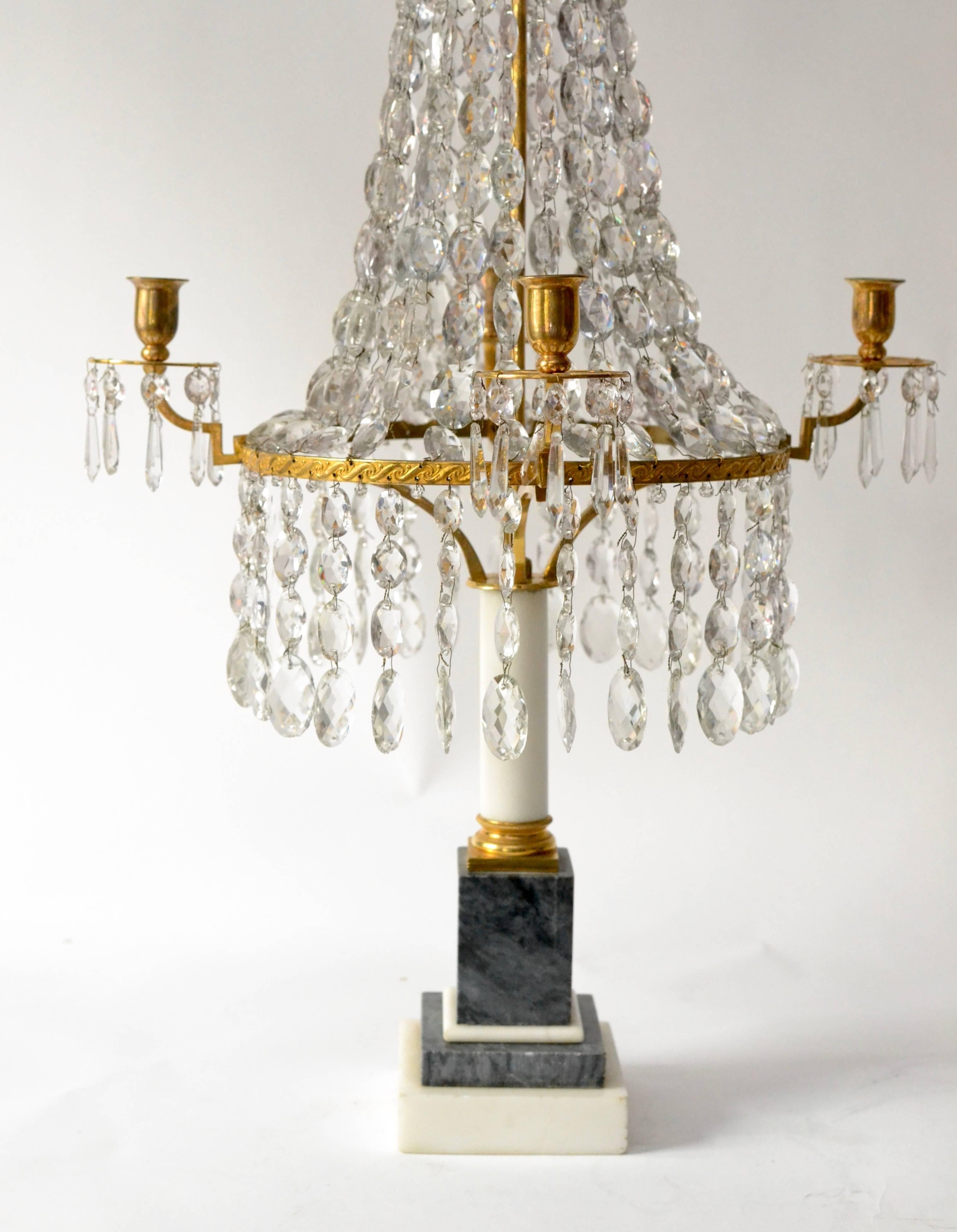 A pair of Louis XVI crystal and gilt bronze candelabra with a marble base.