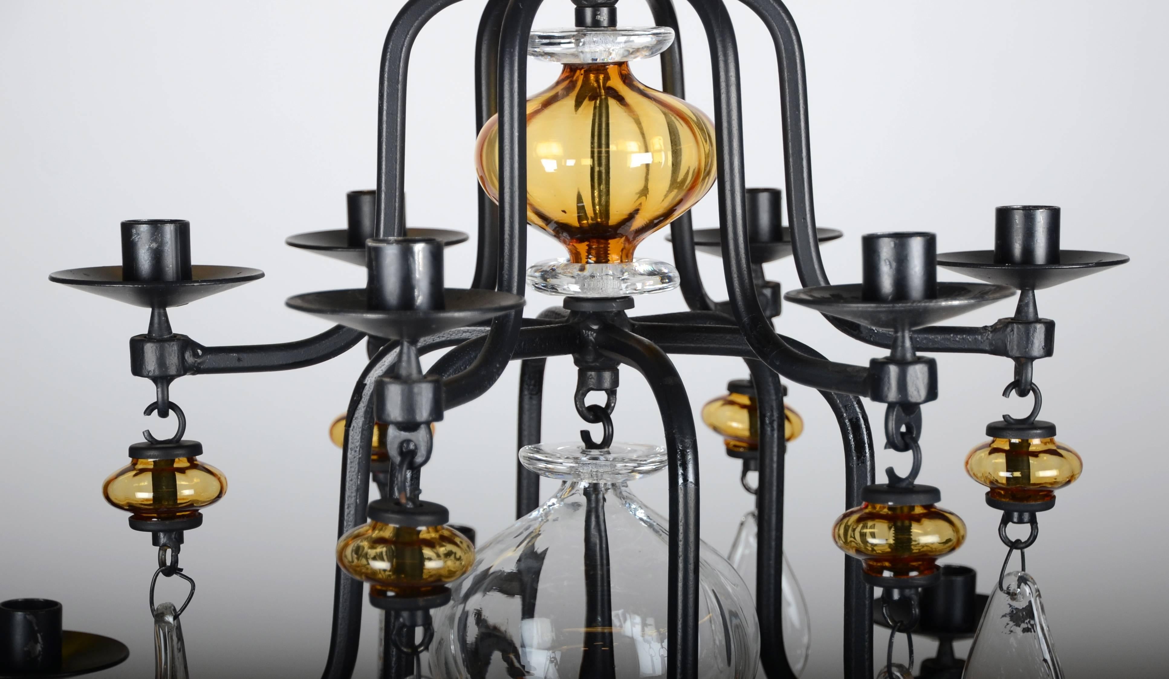 Large twelve-armed candlelit chandelier, designed by Erik Höglund for Boda glasbruk. In ironwork and art glass, 1960-1970s.

Dimensions: Height 96 - 114 cm.