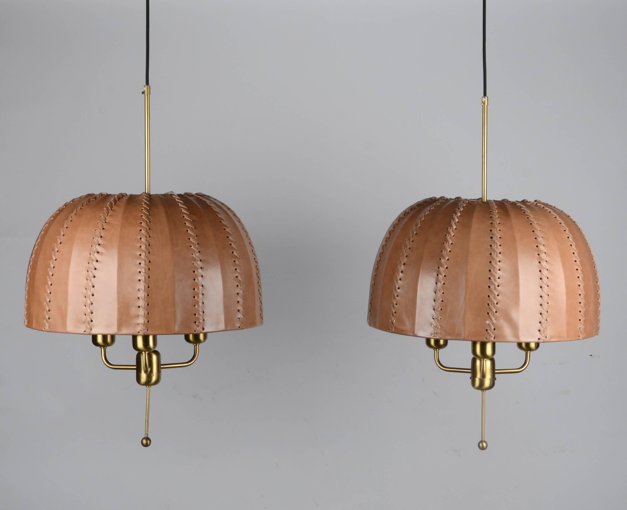 A pair of pendants in brass with leather shades. Designed by Hans-Agne Jakobsson for Markaryd, 1960s-1970s.