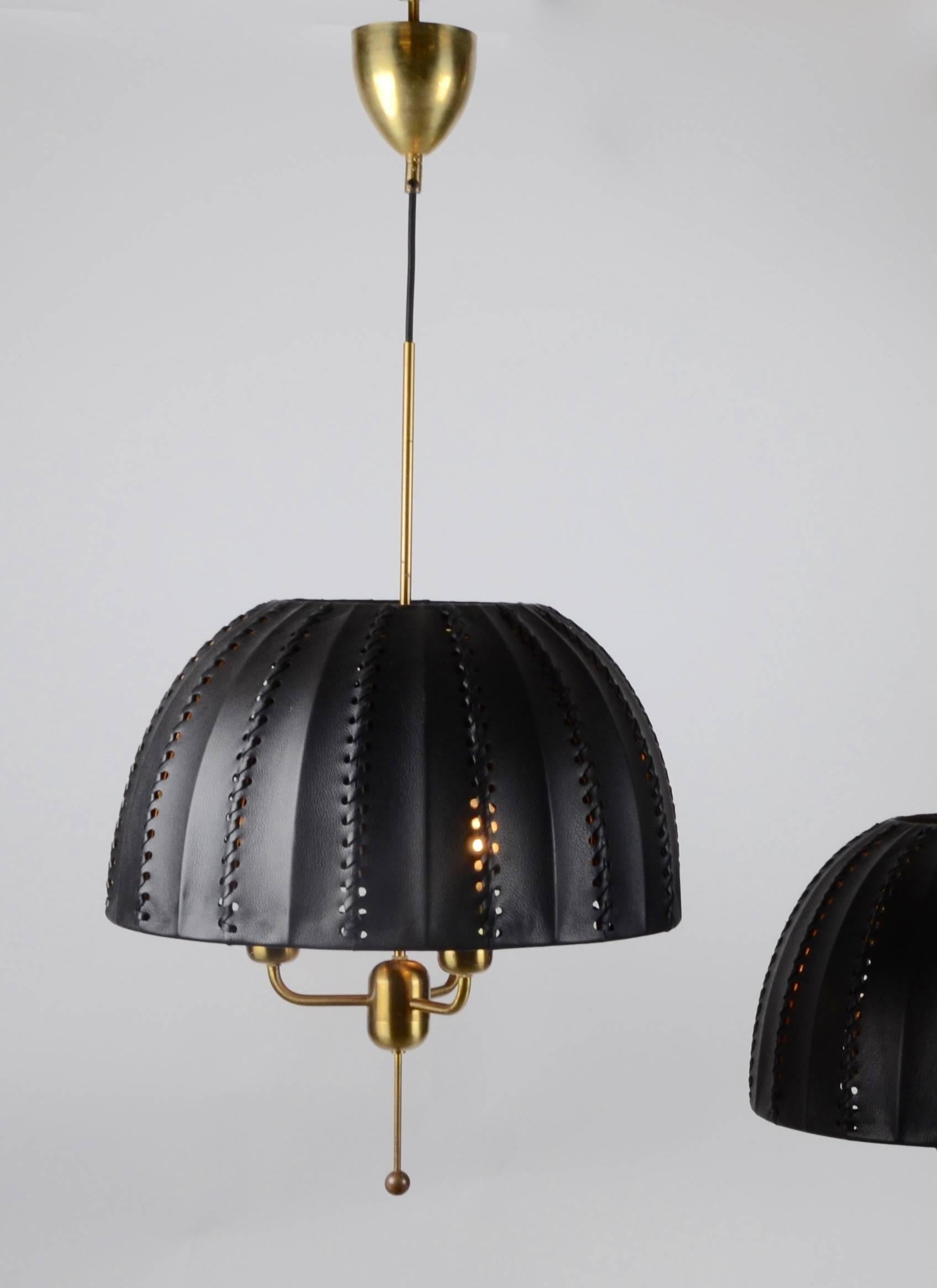 A pair of pendants in brass with leather shades. Designed by Hans-Agne Jakobsson for Markaryd, 1960s-1970s.