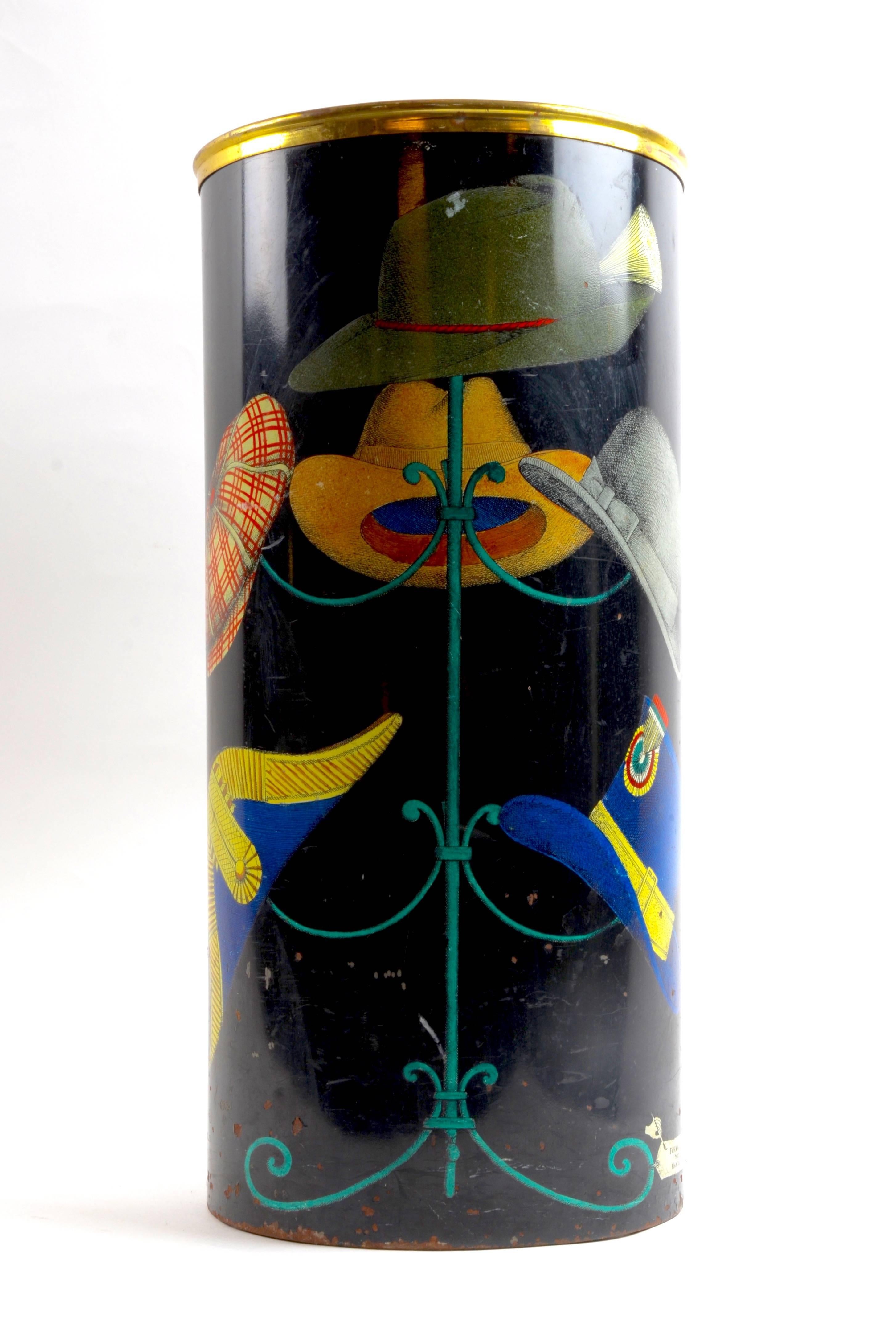 Umbrella Stand designed By Piero Fornasetti, 1950s. Motif of hats in brass, lacquered and lithographic transfer over Masonite board.

Printed label with early Fornasetti mark and hand with paintbrush which reads: Fornasetti Milano made in Italy.