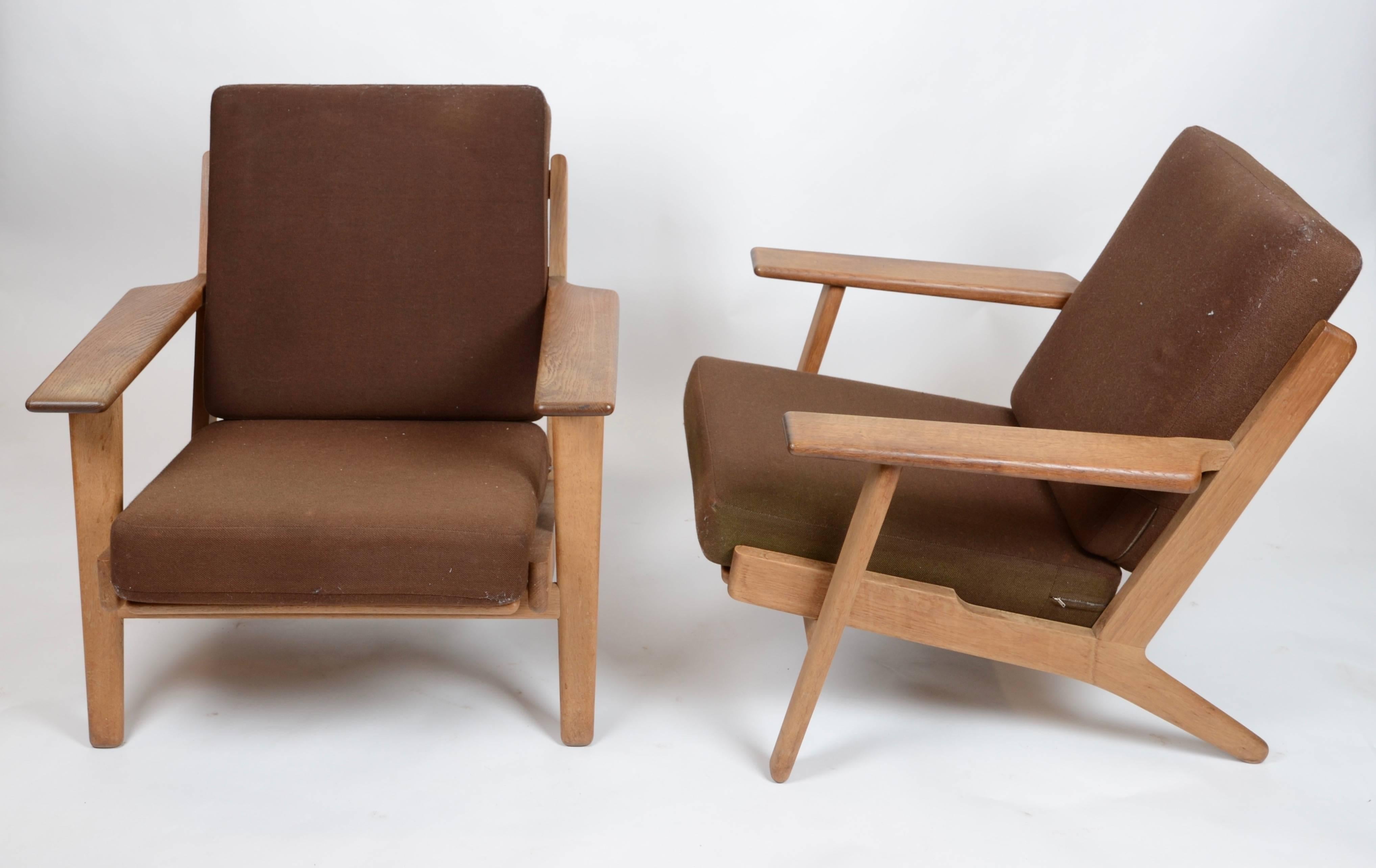 A pair of lounge chair with stools, model GE-290 in oak. Designed by Hans J. Wegner for GETAMA, Denmark, mid-20th century.