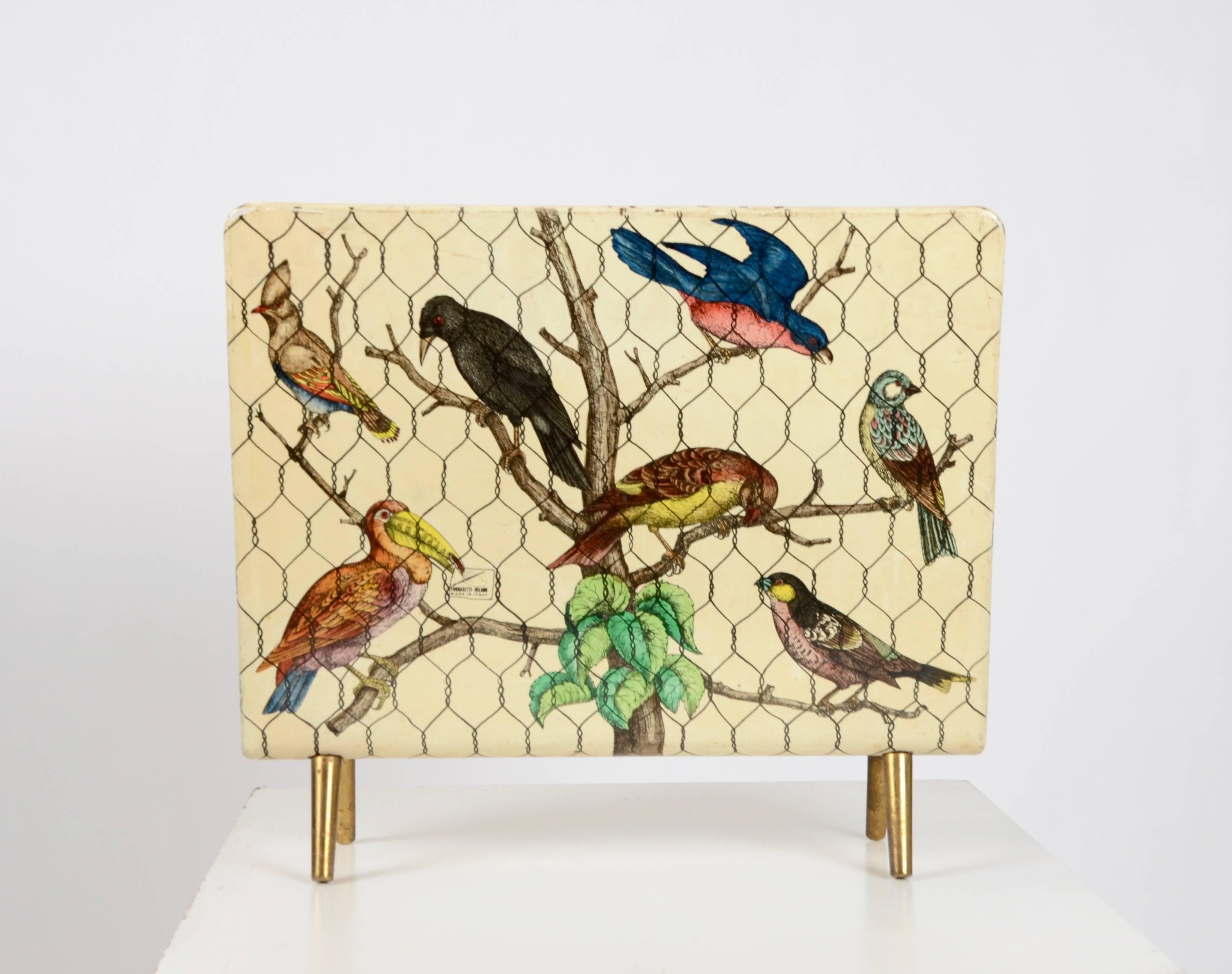 Magazine rack with decor of exotic birds, hand-painted and lithographically printed. With legs and divider in brass. Label: Fornasetti Milano - Made in Italy, 1950s.