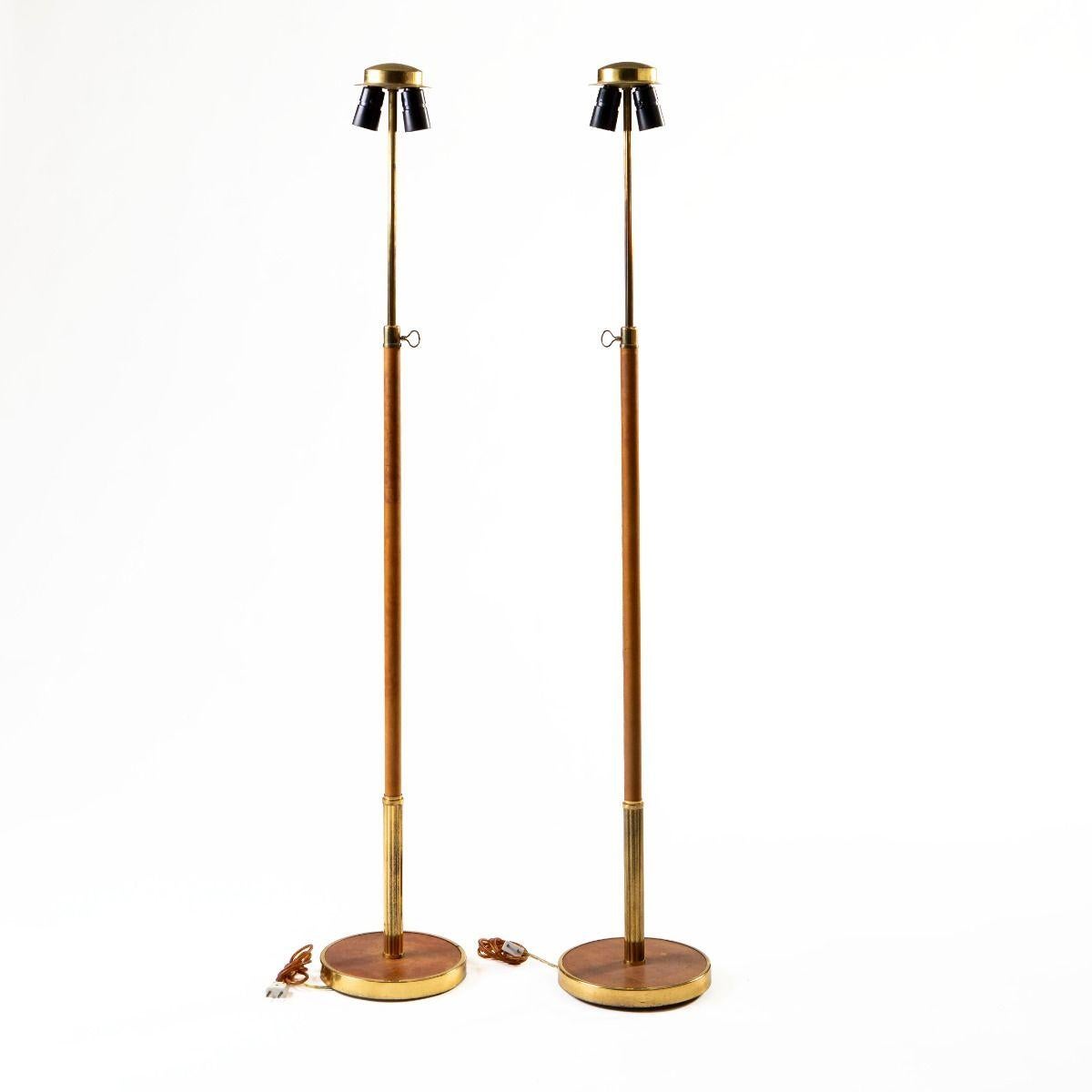 Une paire élégante et bien conservée de lampadaires réglables du célèbre cabinet de design danois Lysberg, Hansen & Therp.

Ces lampes élégantes sont fabriquées en laiton massif avec des bases rondes lestées et des tiges fines enveloppées de cuir de