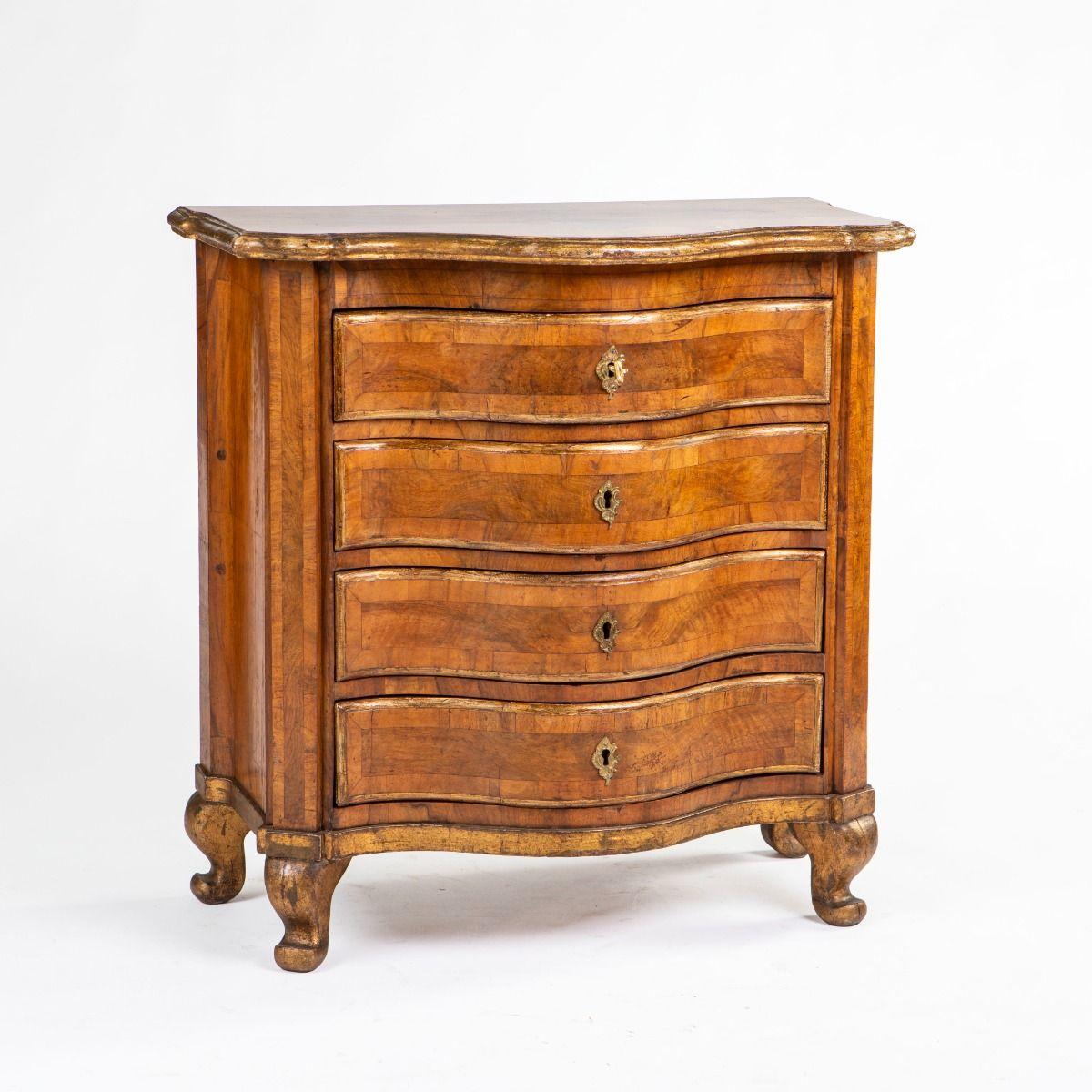 Elegant Danish baroque commode with serpentine front.
Beautifully and originally veneered in thick, hand-cut walnut and walnut burl, arranged in framed panels.
The top features a profiled and gilded edge; mouldings and profiles are likewise