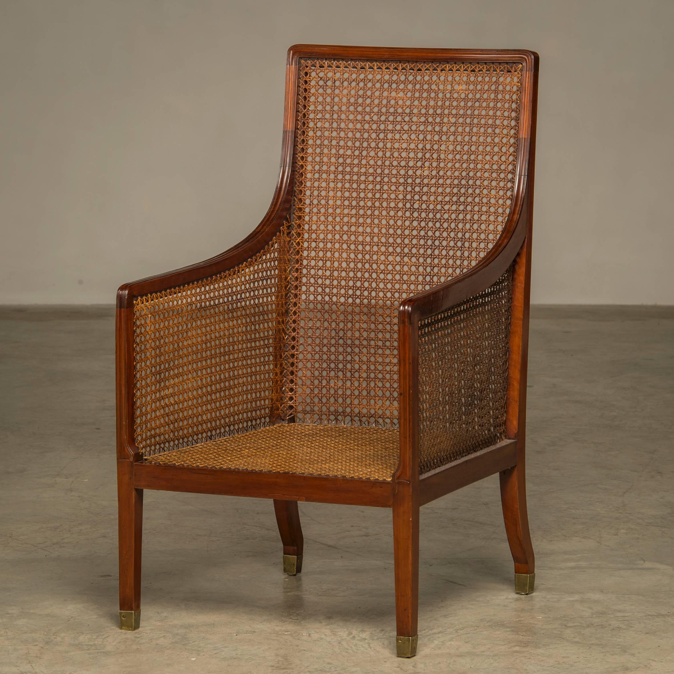 Elegant regency armchair in mahogany with cane in the sides, back and seat. Legs with brass shoes, 
England, circa 1820. 
Loose cushions reupholstered with velvet.