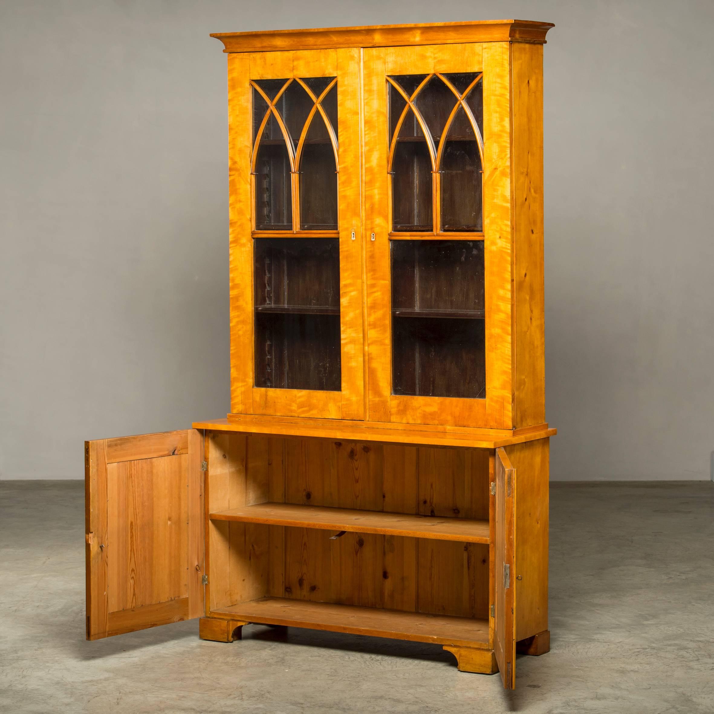 Carl Johan bookcase, Gothic inspired, made of light birch. Top with a pair of glass doors, base with a pair of doors behind which shelves, Sweden, circa 1820.