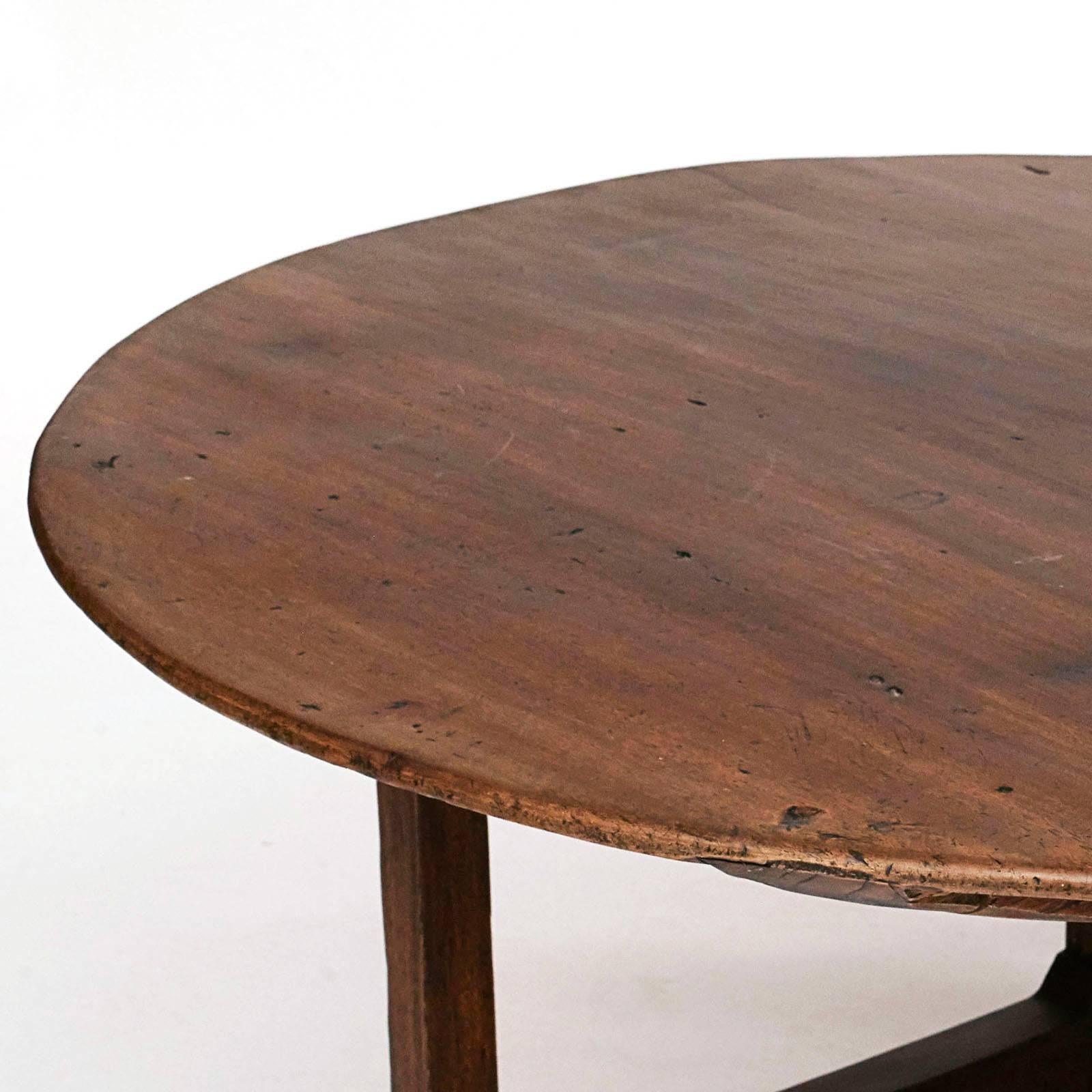 A Spanish Colonial narra wood table, mid-19th century, the near circular top above four straight supports and raised on charming carved boot form feet joined by a H-form stretcher. Very good patina.