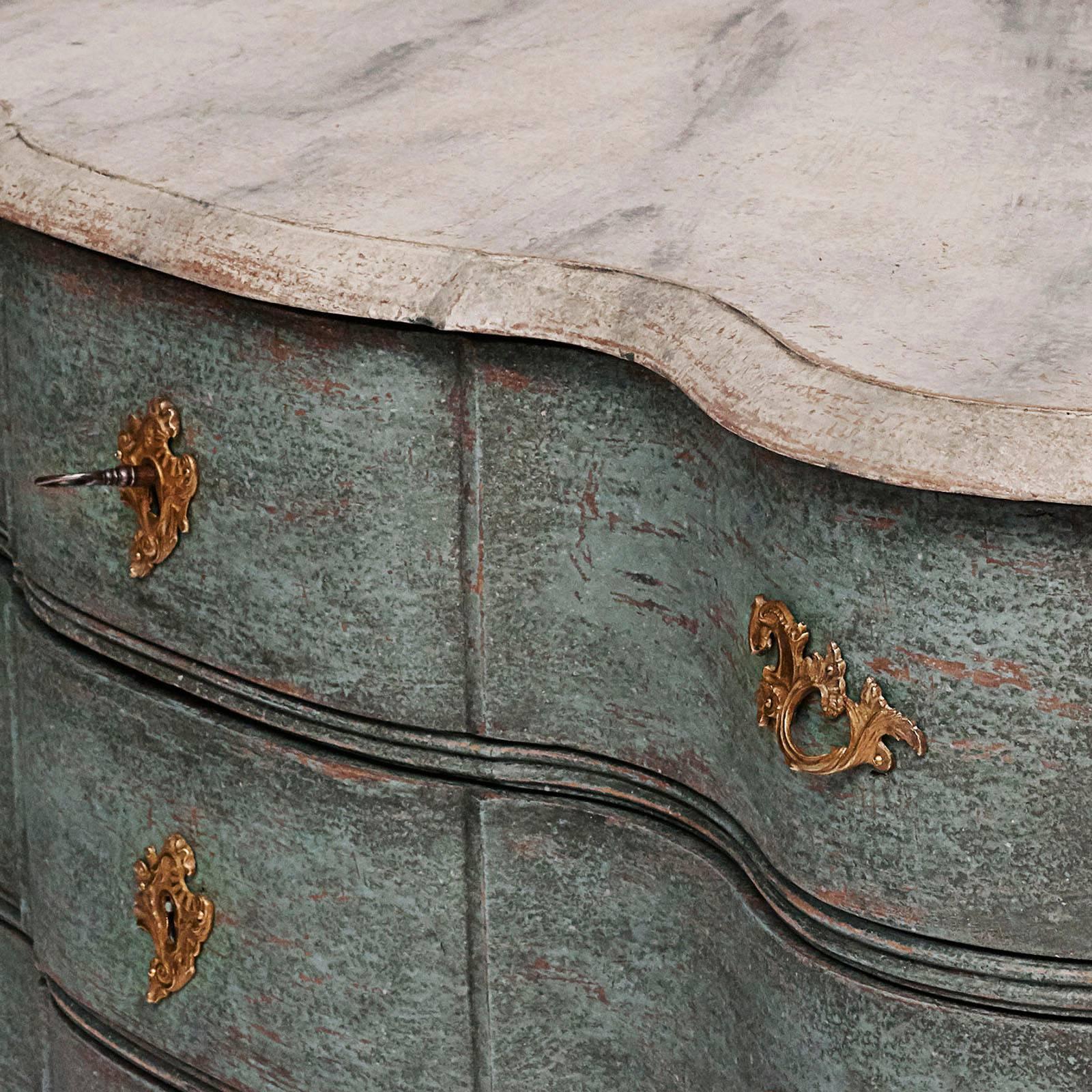 A rare Danish Baroque painted commode, mid-18th century, the overhanging top above four long serpentine drawers and conforming sides, a lower molded frieze raised on high stylized animal legs ending in paw feet and headed with acanthus leaf carving.