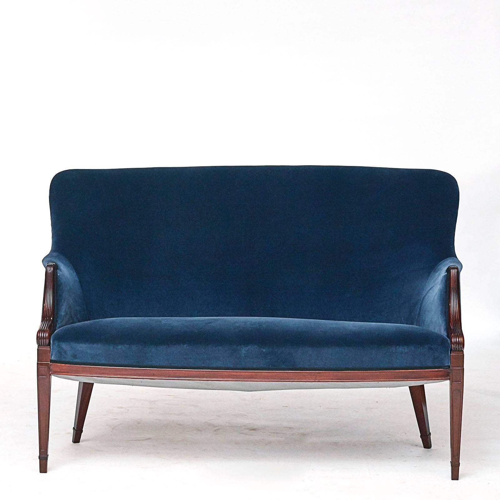 A Danish sofa by Frits Henningsen, circa 1940s, with an upholstered back and seat, channelled scrolled armrests raised on square tapered legs. 
New rich dark blue velvet upholstery.
