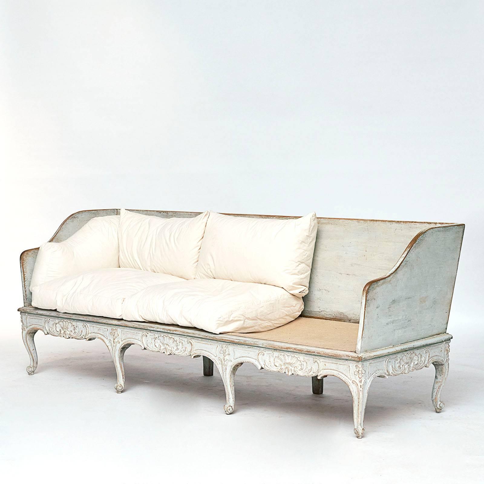 A good Swedish Rococo painted sofa, last quarter 18th century with a straight back and slightly curved armrests and loose white cotton feather filled cushions, a scrolled and shell carved frieze raised on cabriole legs.

 