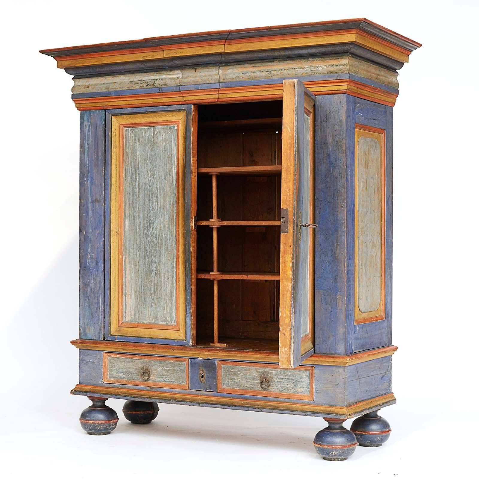 A massive Danish Baroque polychrome cabinet, mid-18th century, with an impressive overhanging stepped molded cornice, two panelled cupboard doors above one long drawers, made to look like two drawers, raised on bun feet.
Original paint surface.