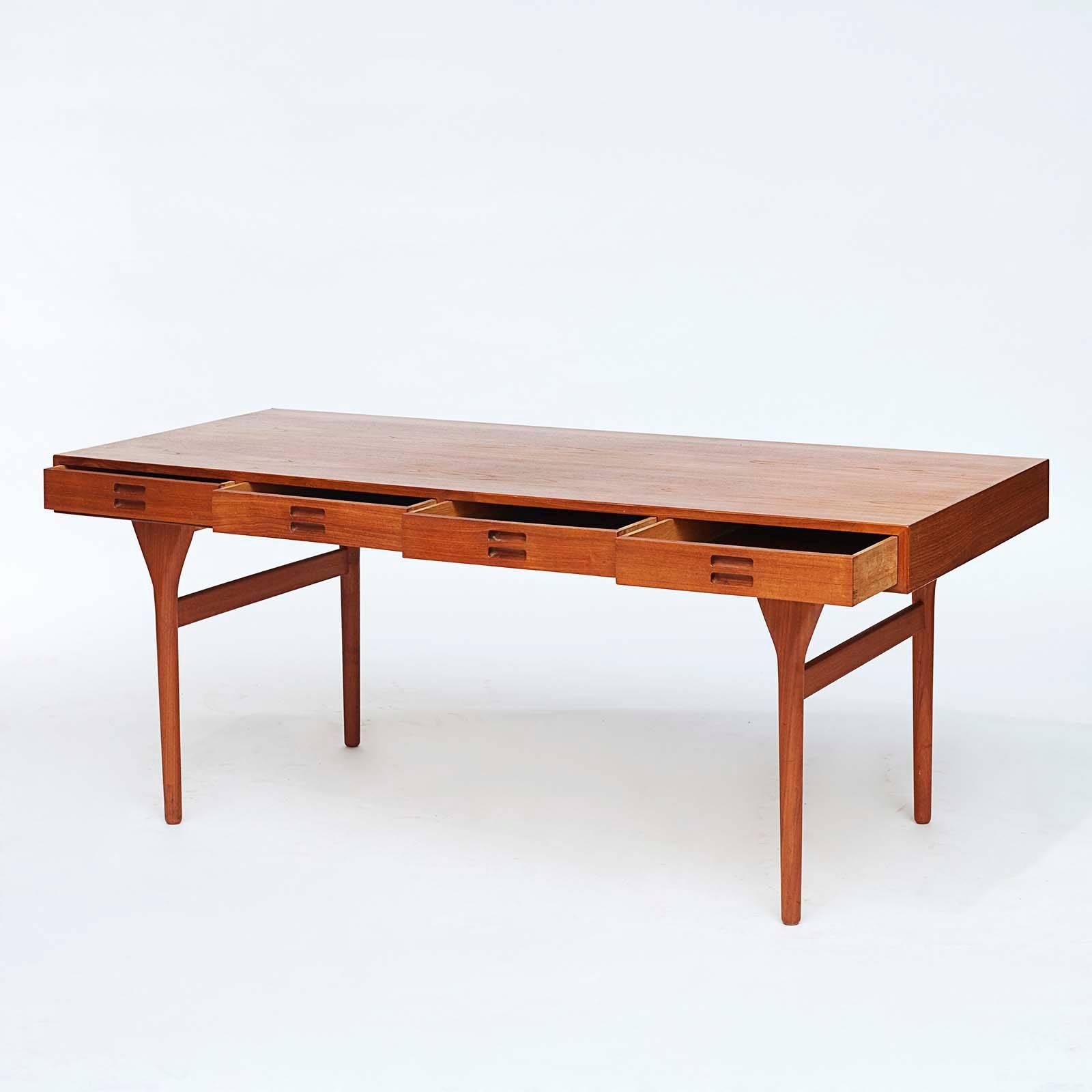 A Danish teakwood writing desk designed by Nanna Ditzel and produced by Søren Willadsen, Vejen, Model #93-4. Original design, circa 1958. The rectangular top with four frieze drawers with recessed drawer pulls, raised on circular tapering