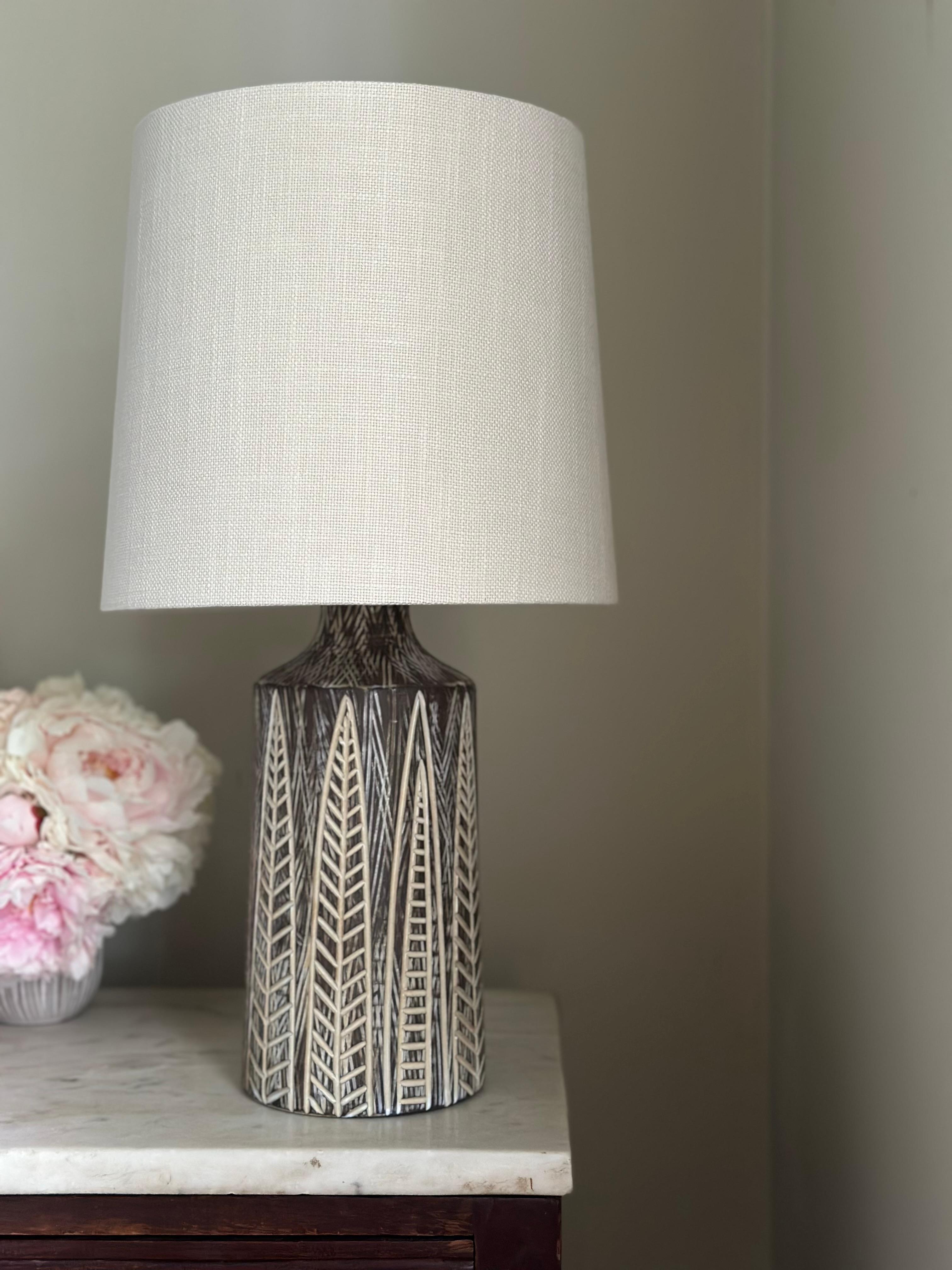 Swedish Art Deco Table Lamp NIGERIA in Stoneware from Upsala-Ekeby. Model 4275 by Mari Simmulson in earthenware glazed with a graphic hand-carved decor over matte brown. Hand thrown stoneware during the 1950s. 
Very similar Ekeby SENEGAL.
New wiring