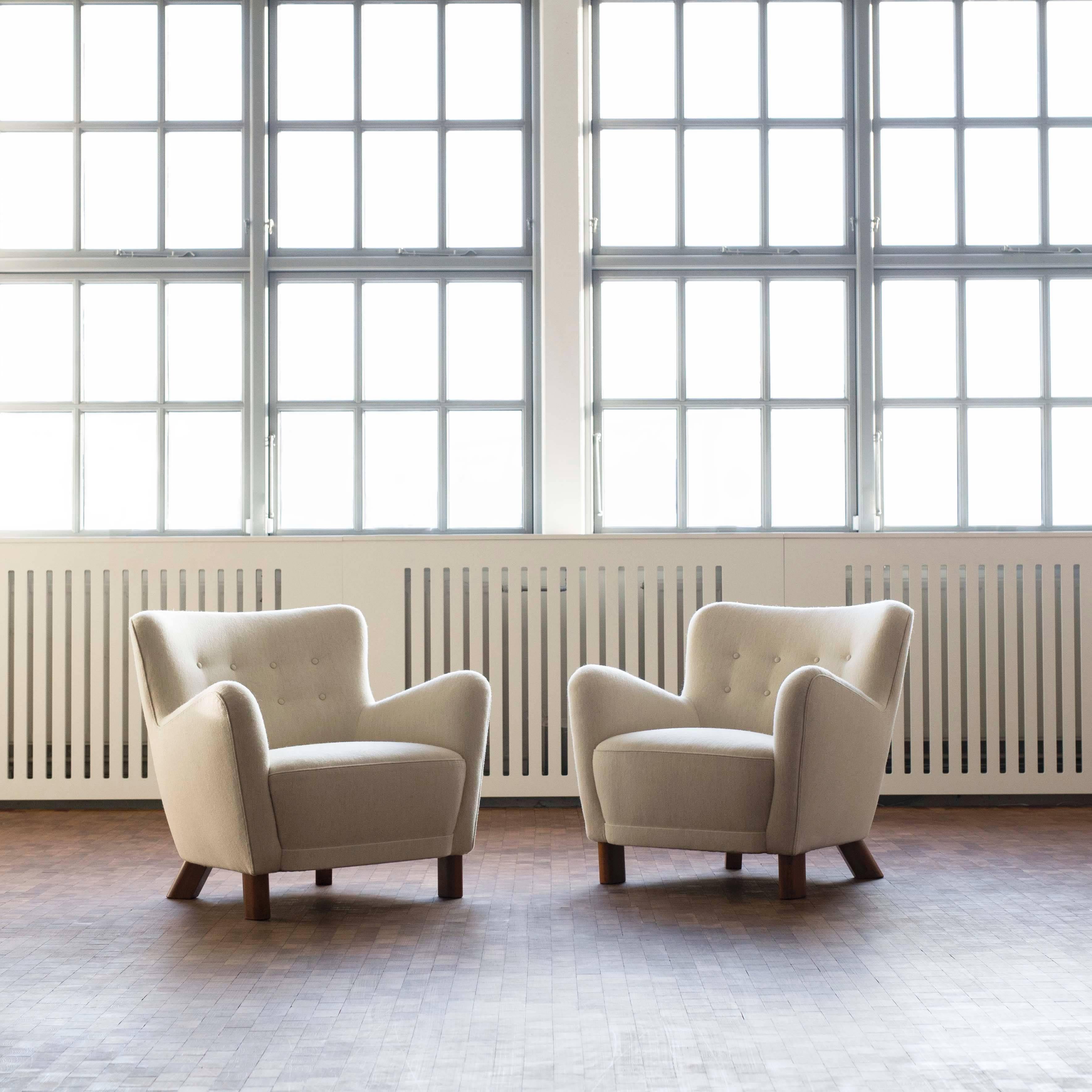 A pair of sculptural easy chairs. 

Designed in the late 1930s and made by Fritz Hansen as model 1669 with maker's stamp to the frame. 

Legs of stained beech, new upholstery with light beige fabric, executed as original. Please contact us for