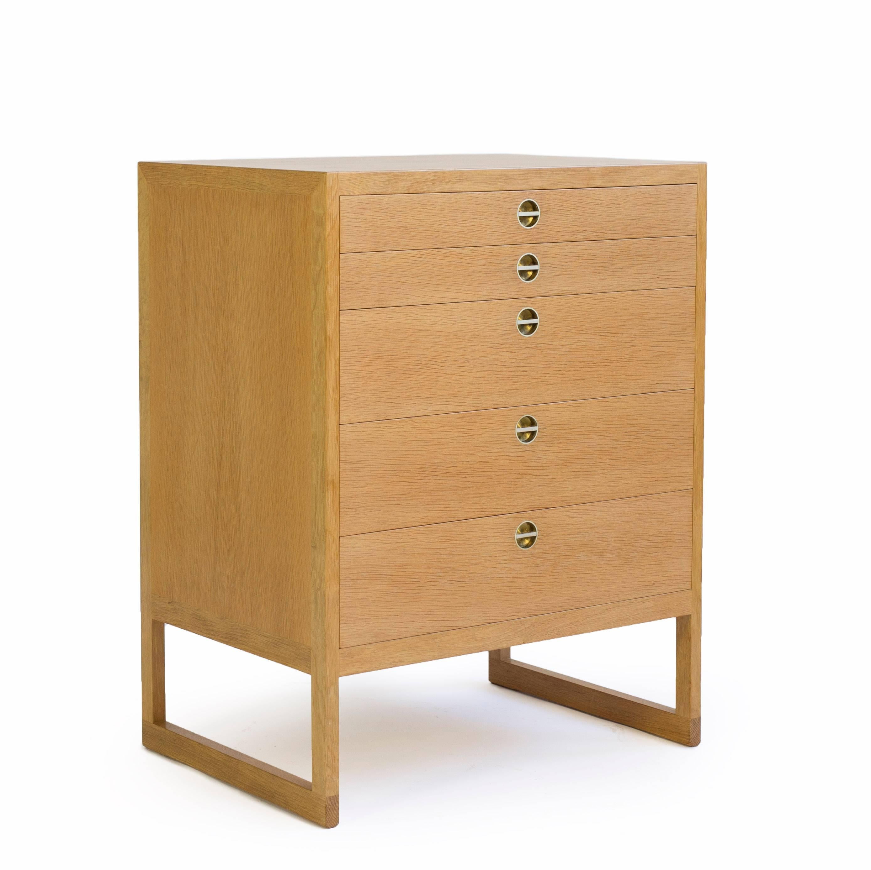 A Børge Mogensen oak chest of five drawers with brass handles. 

Designed by Børge Mogensen 1957, manufactured by cabinetmaker P. Lauritsen & Son, Denmark. 


