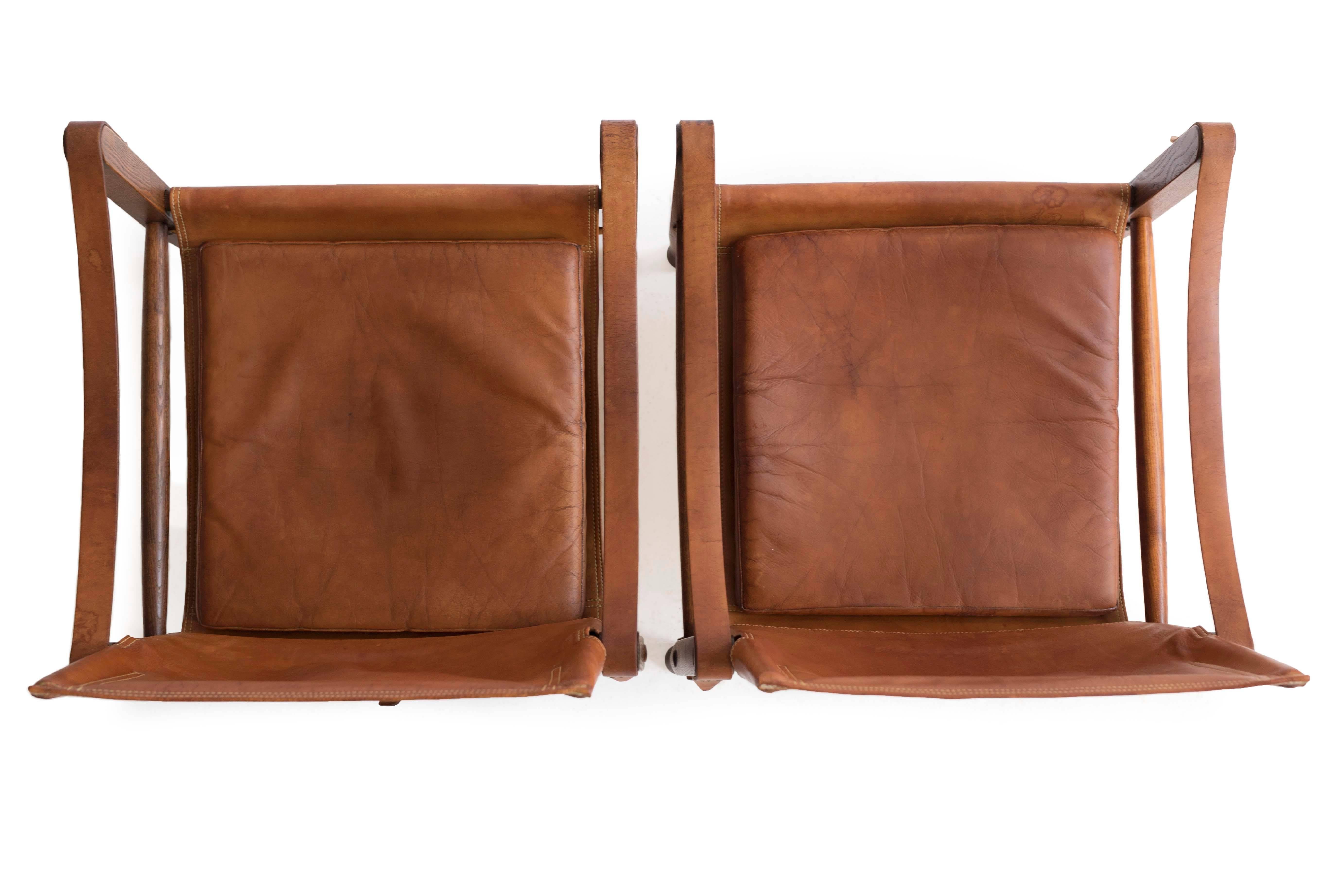 A pair of Kaare Klint 'Safari chairs.' 

Frames of stained ash, upholstered with original patinated leather. 

Designed by Kaare Klint, 1933, manufactured by Rud. Rasmussen, Copenhagen, Denmark. 

Original condition with some natural wear.
