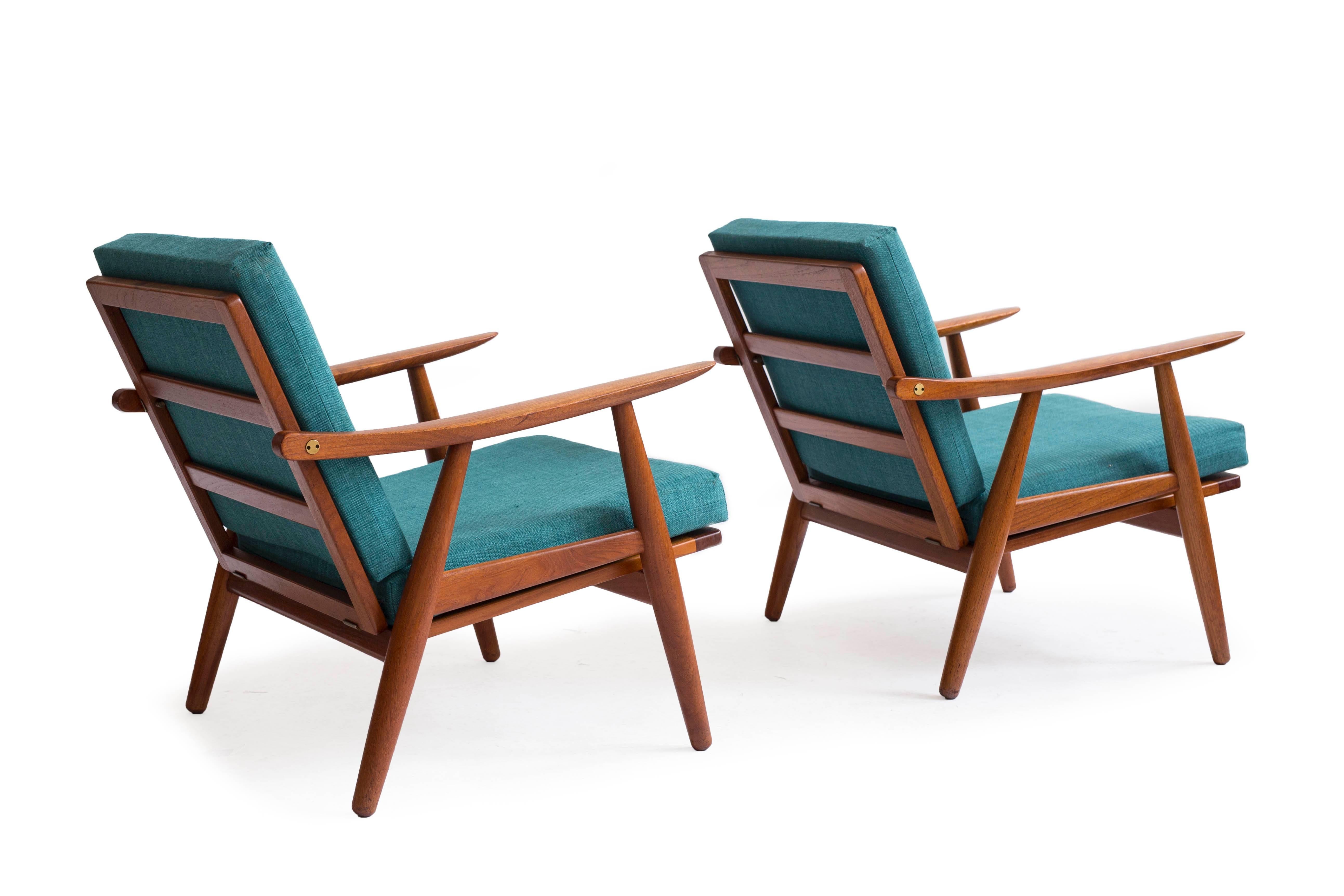 A pair of Hans J. Wegner teak GE270 easy chairs with original loose fabric cushions and brass details. 

Designed by Hans J. Wegner 1950, manufactured by GETAMA, Denmark.
Both chairs burn marked by maker.
Fine original condition.