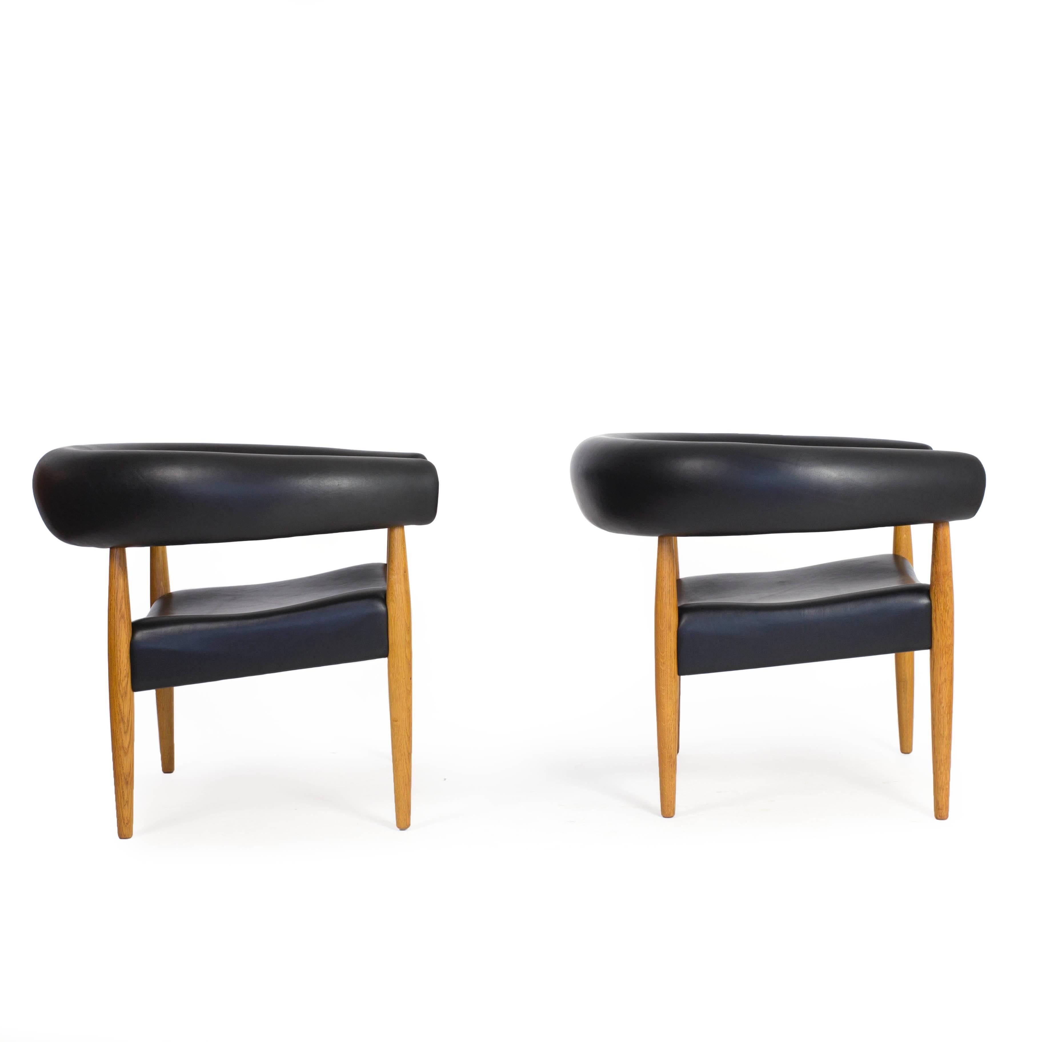 A pair of Nanna Ditzel 'Pølse stolen' with frames of oak, seat and back upholstered with black dyed natural leather. 

Designed by Nanna Ditzel 1958 as 'The sausage chair' and made by Kolds Savvaerk, Denmark. 
The later edition was renamed 'The