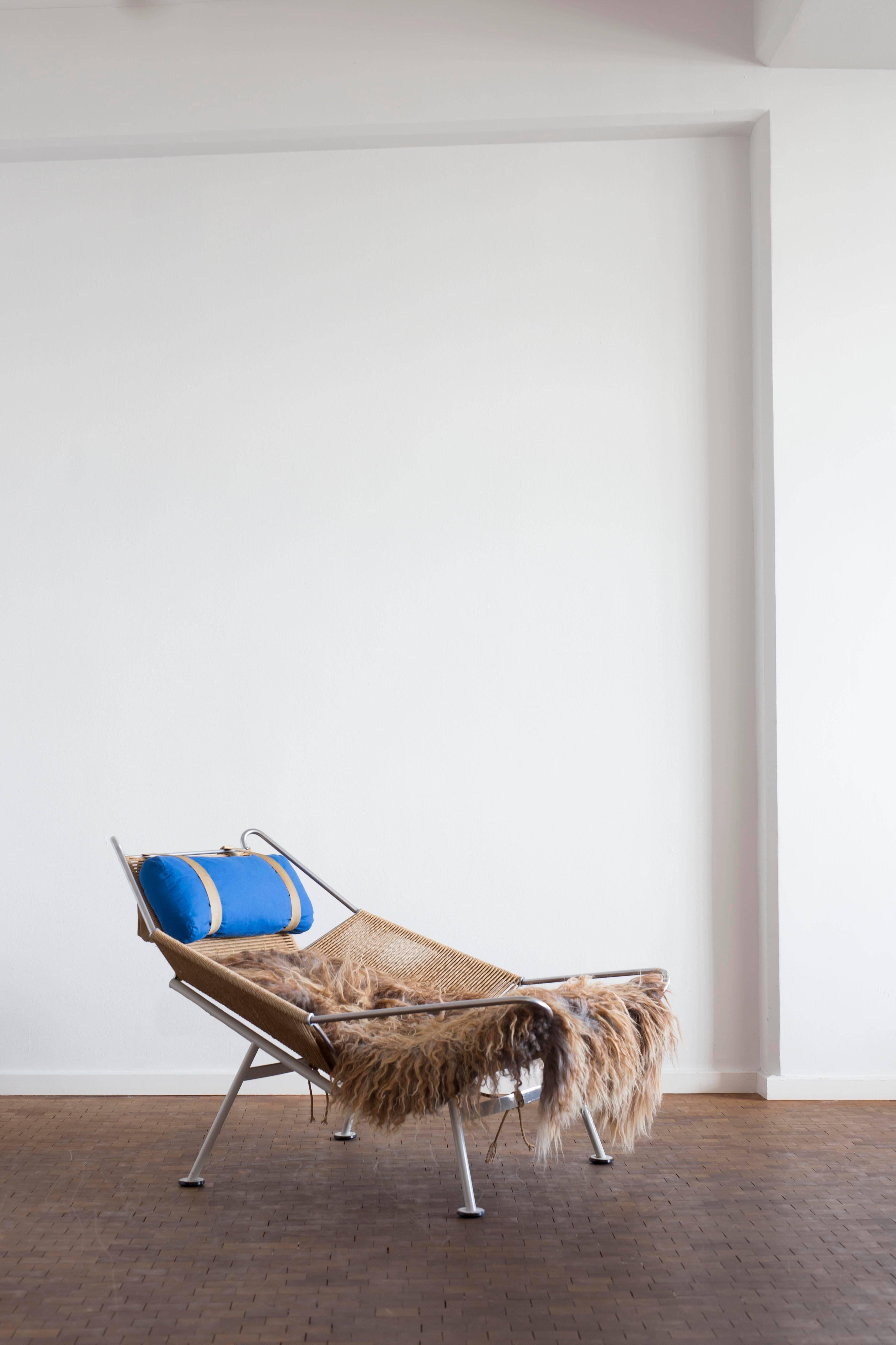Hans J. Wegner flag halyard easy chair with original white lacquered steel frame, cushion in blue fabric and a sheepskin throw. 

Designed by Hans J. Wegner in 1950 and manufactured by GETAMA, Denmark, circa end of 1950s-1960s, model GE225.

Very