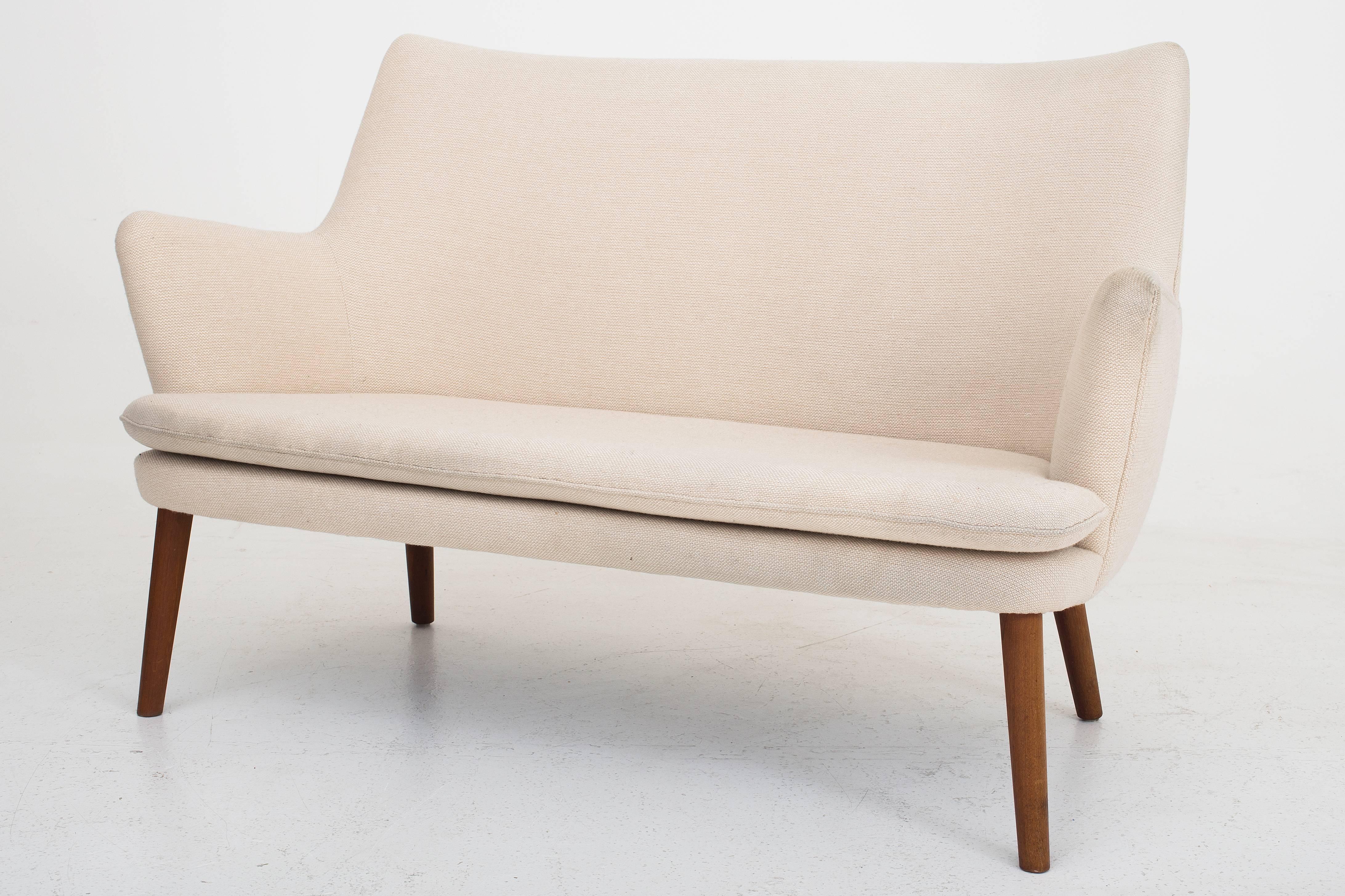 Two-seat sofa with original white cream colored fabric and legs in teak. Model AP 20. Manufactured by AP Stolen, Denmark.
