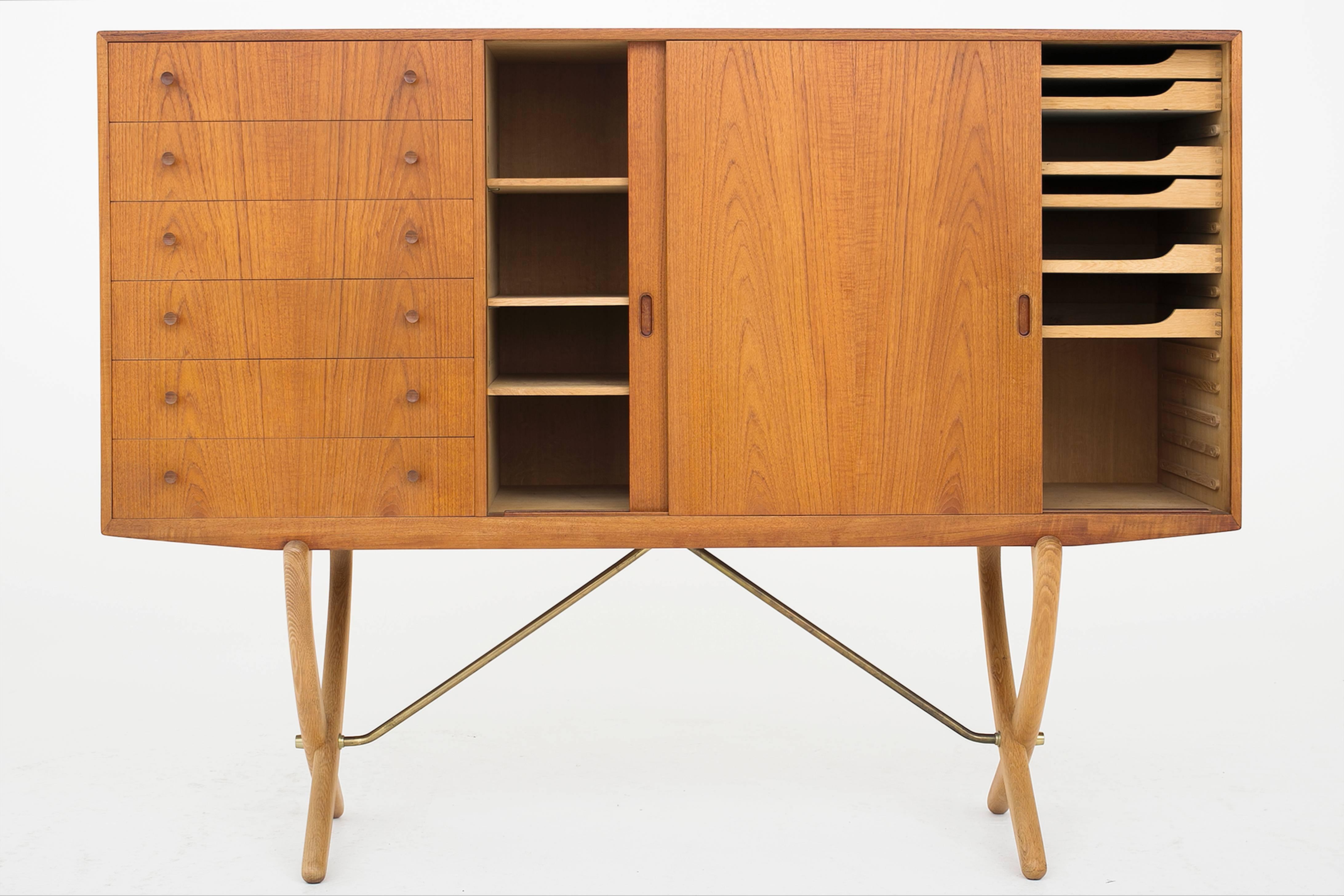 Hans J. Wegner sideboard model CH 304. Cabinet in teak with sliding doors and six front drawers, legs in oak and brass. Designed by Carl Hansen, 1950.
             