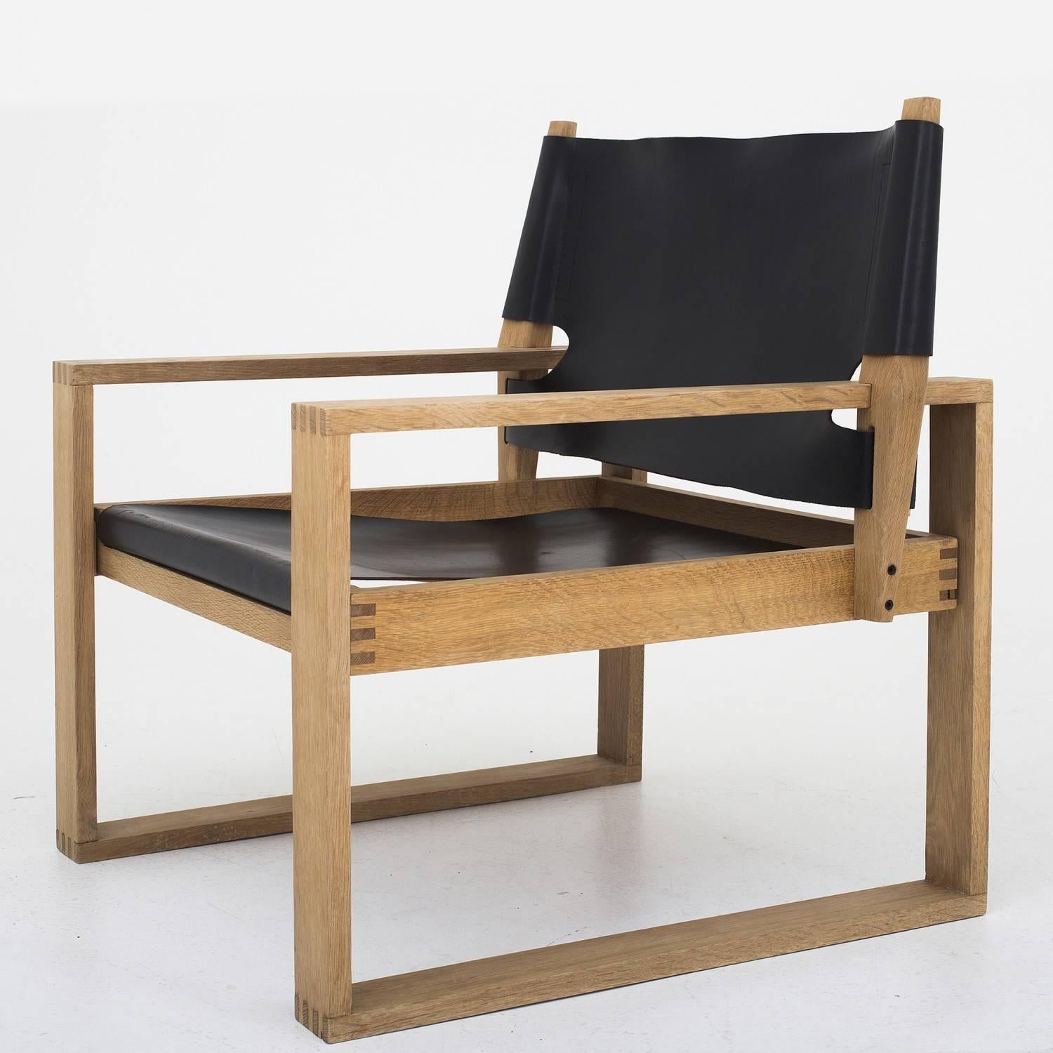 A pair of lounge chairs in oak and patinated leather. Designed by Svend Frandsen. Maker Hugo Frandsen.