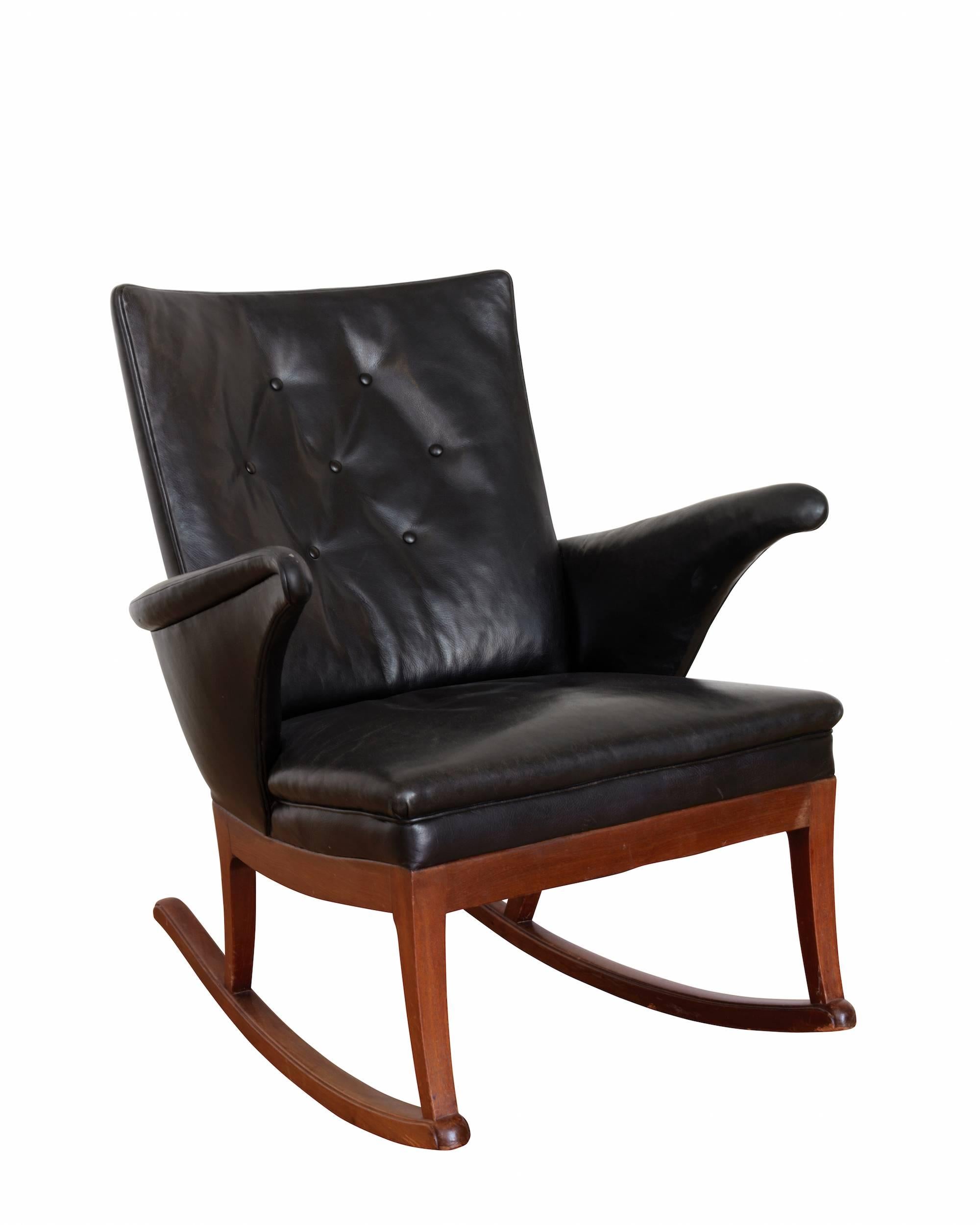 Rocking chair and matching stool with mahogany frame, upholstered in patinated black leather. Manufactured by Frits Henningsen in the 1950s.