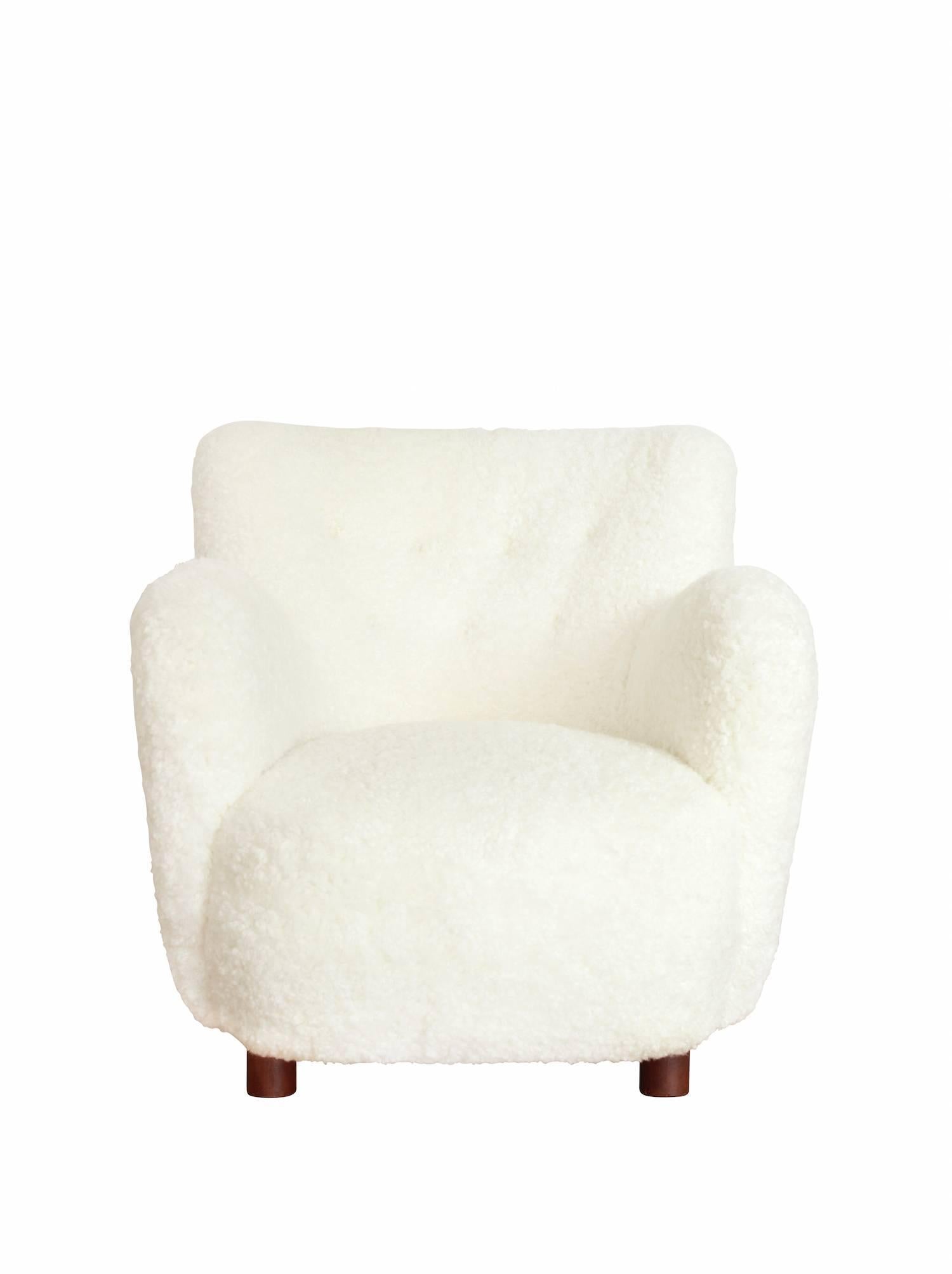 Free standing lounge chair upholstered with white sheepskin, raised on round legs of beech.