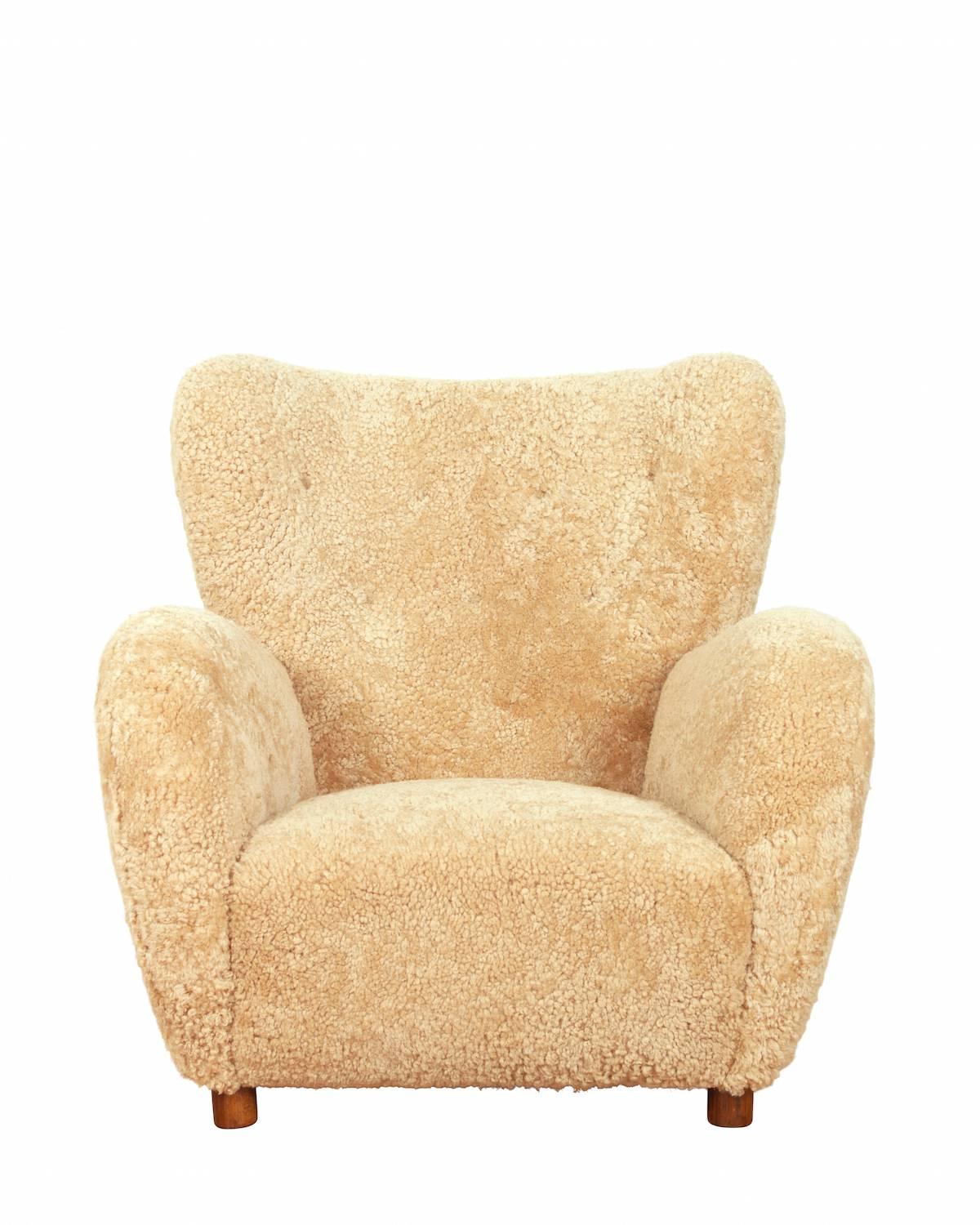 High back easy chair upholstered in brown sheepskin, raised on legs of beech.