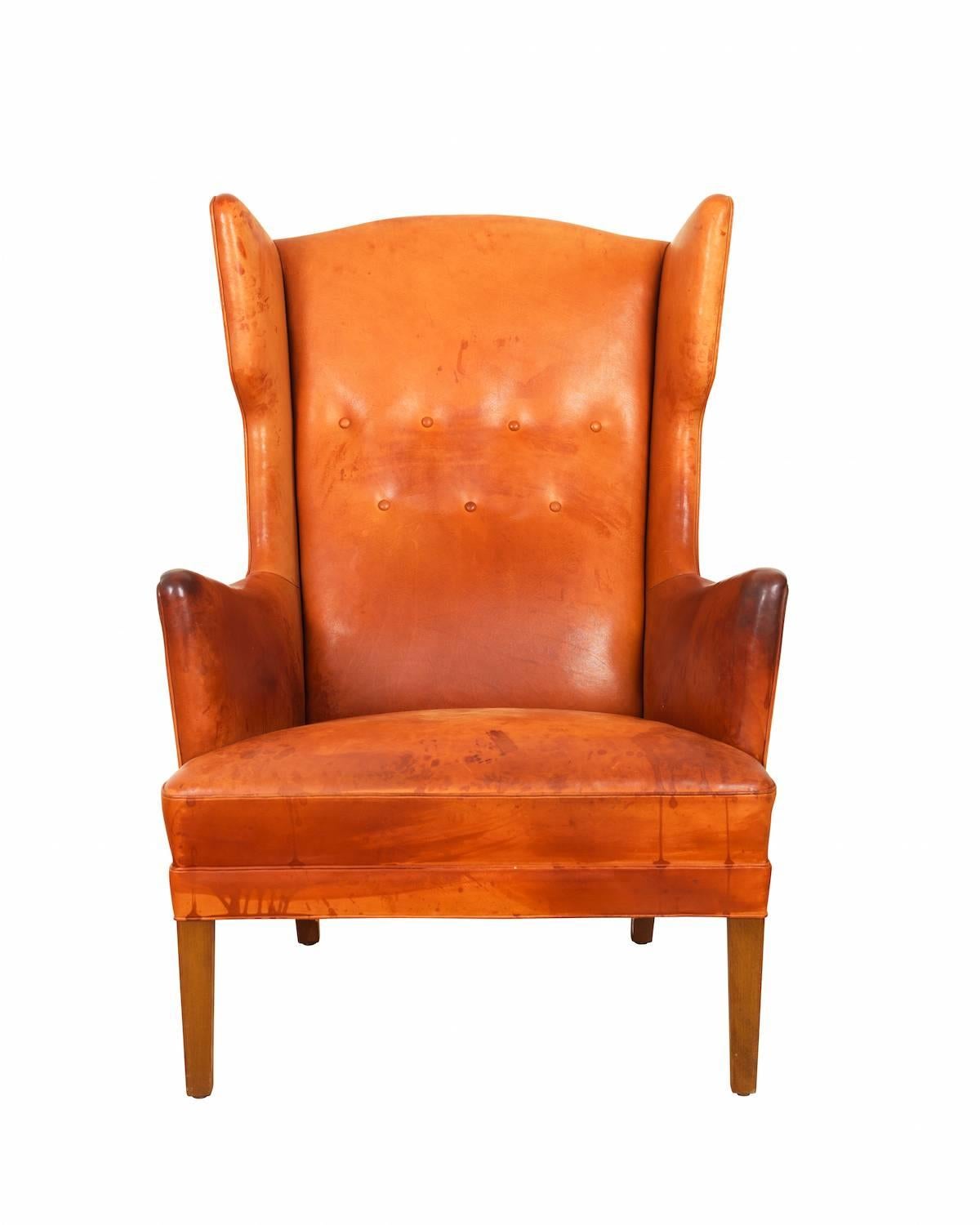 Rare wing chair by Frits Henningsen, dated 1950s with original cognac vegetal leather upholstery.

Slightly curved armrests, square and slightly tapered dark-stained wood legs.

Leather with patina.

Produced by master cabinetmaker Frits