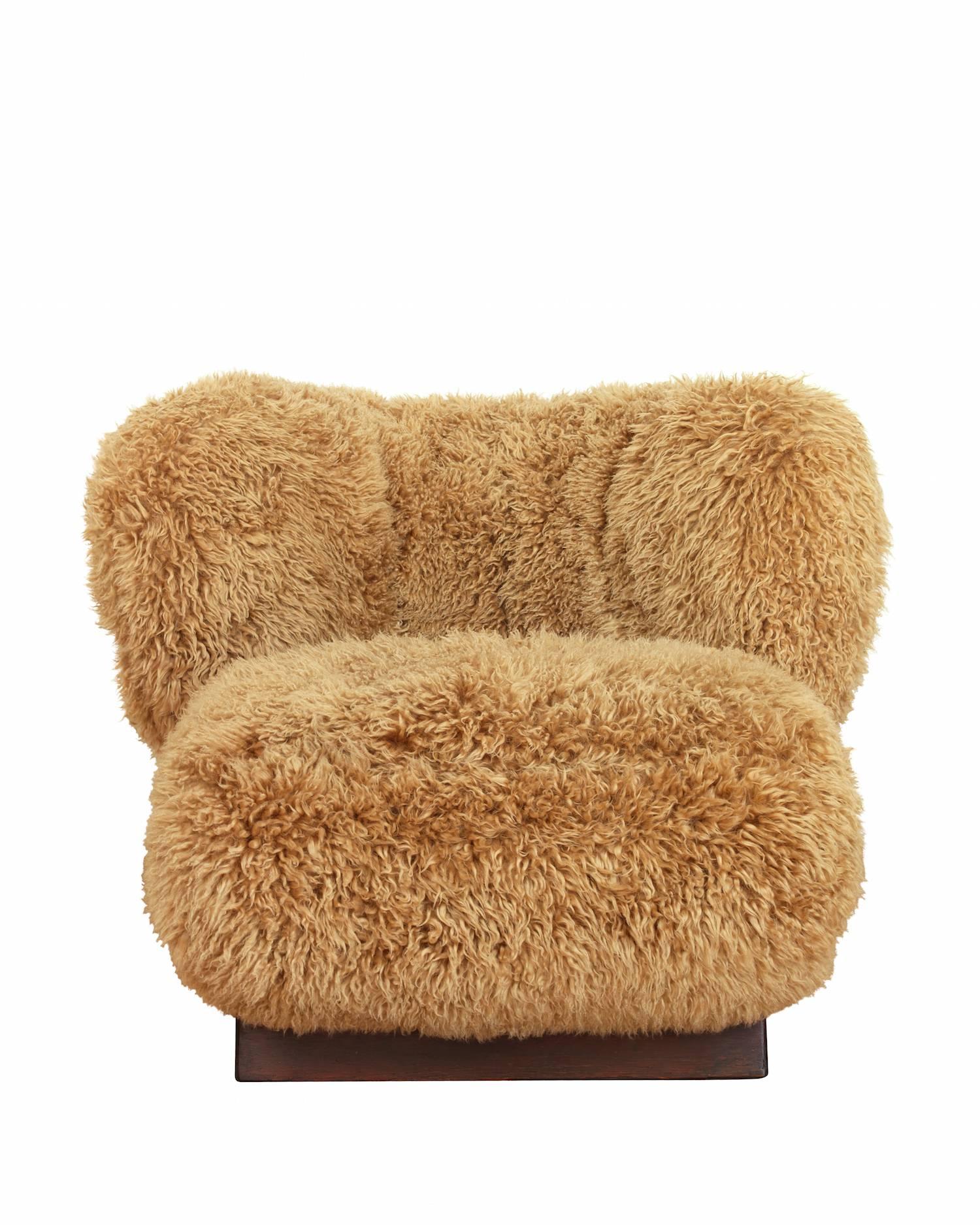 Danish design easy chair upholstered with brown sheepskin, raised on three legs of browned oak.