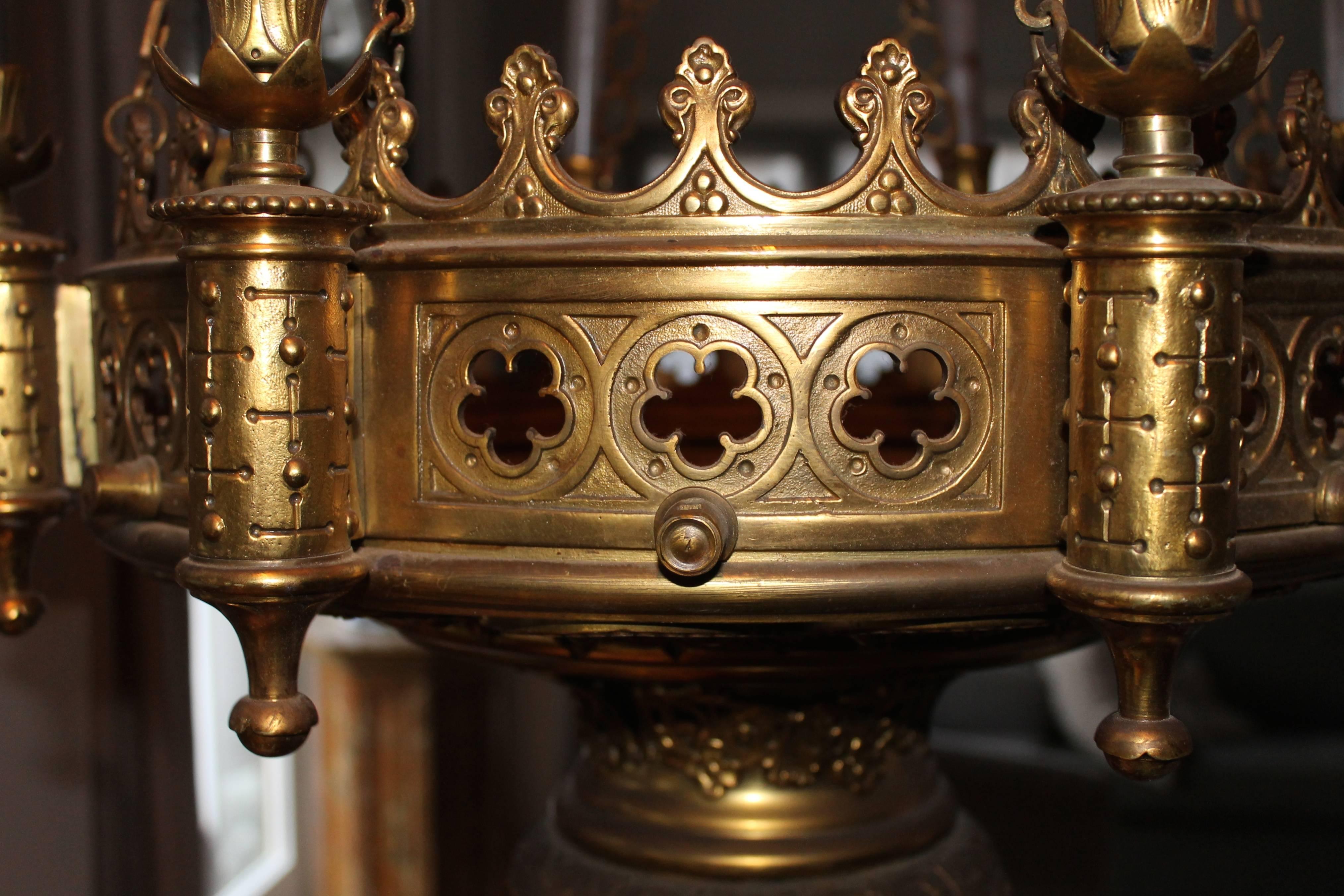 Chandelier in brass for eight candles, decorated with ornaments and flowers.