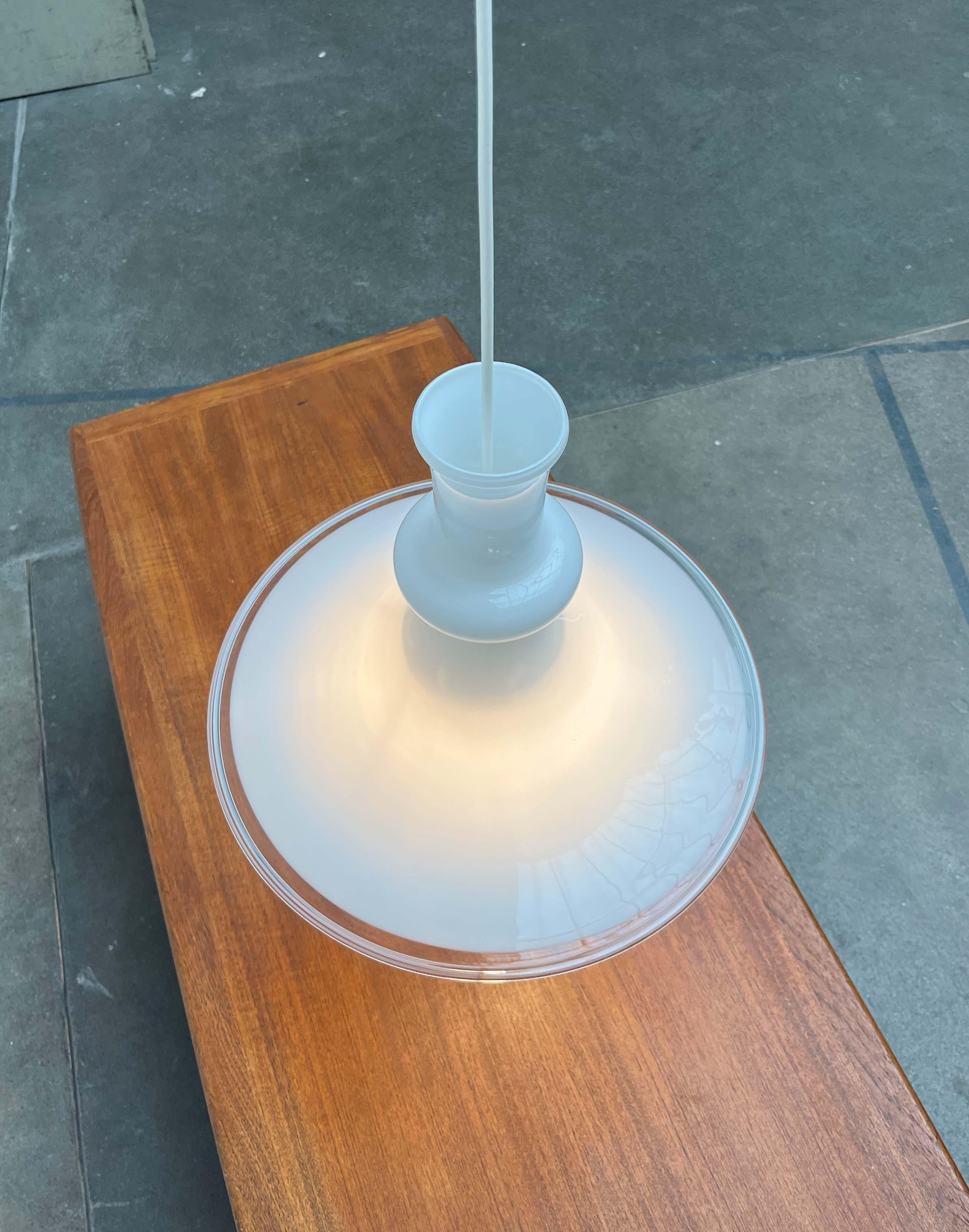 Lampada a sospensione in vetro ornamentale del produttore danese Royal Copenhagen / Holmegaard e disegnata da Michael Bang negli anni '70.

un corpo rotante in vetro opalino viene utilizzato come diffusore con rigonfiamenti caratteristici. Il vetro