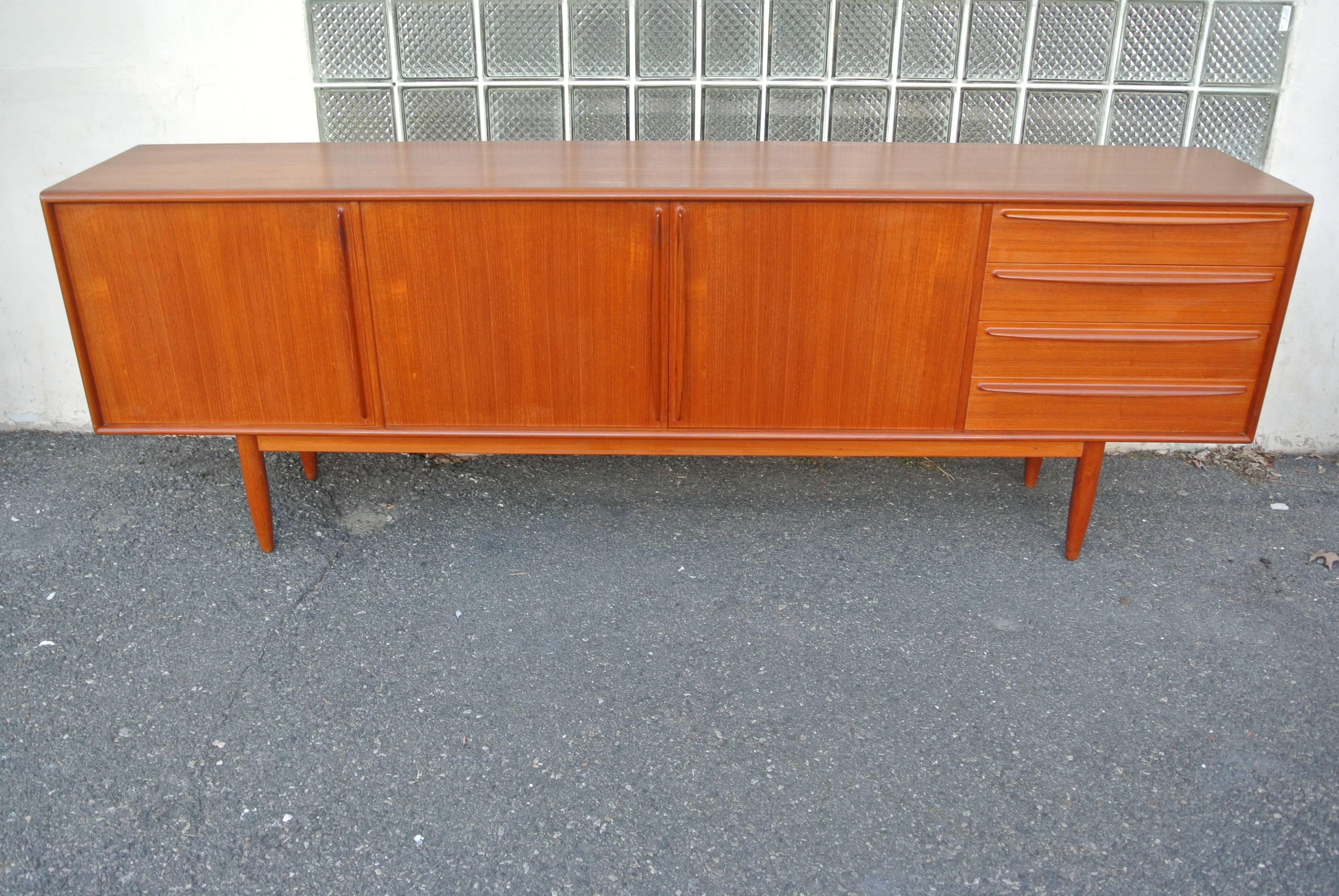Beautiful 8' teak sideboard by Bernhard Pedersen & Son. 
The left compartment is designed to house a wet bar. the middle two doors open and expose storage with two shelves on each side. And the right houses four individual drawers, with the top