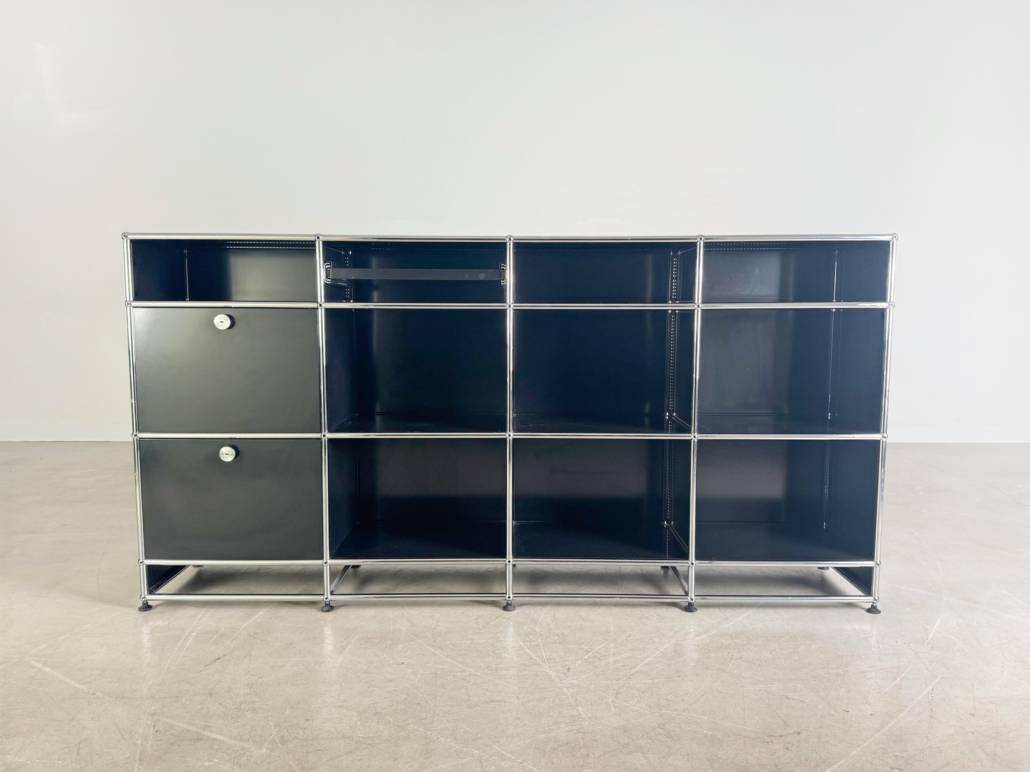 Ti offriamo una splendida credenza Usm Haller Regal in nero. Das Möbel is vier Moduleinheiten hoch und vier breit, wovon die unterste Reihe nur eine Erhöhung ohne Einlegeböden darstellt. Damit bietet das Board insgesamt 12 Fächer, wovon zwei mit