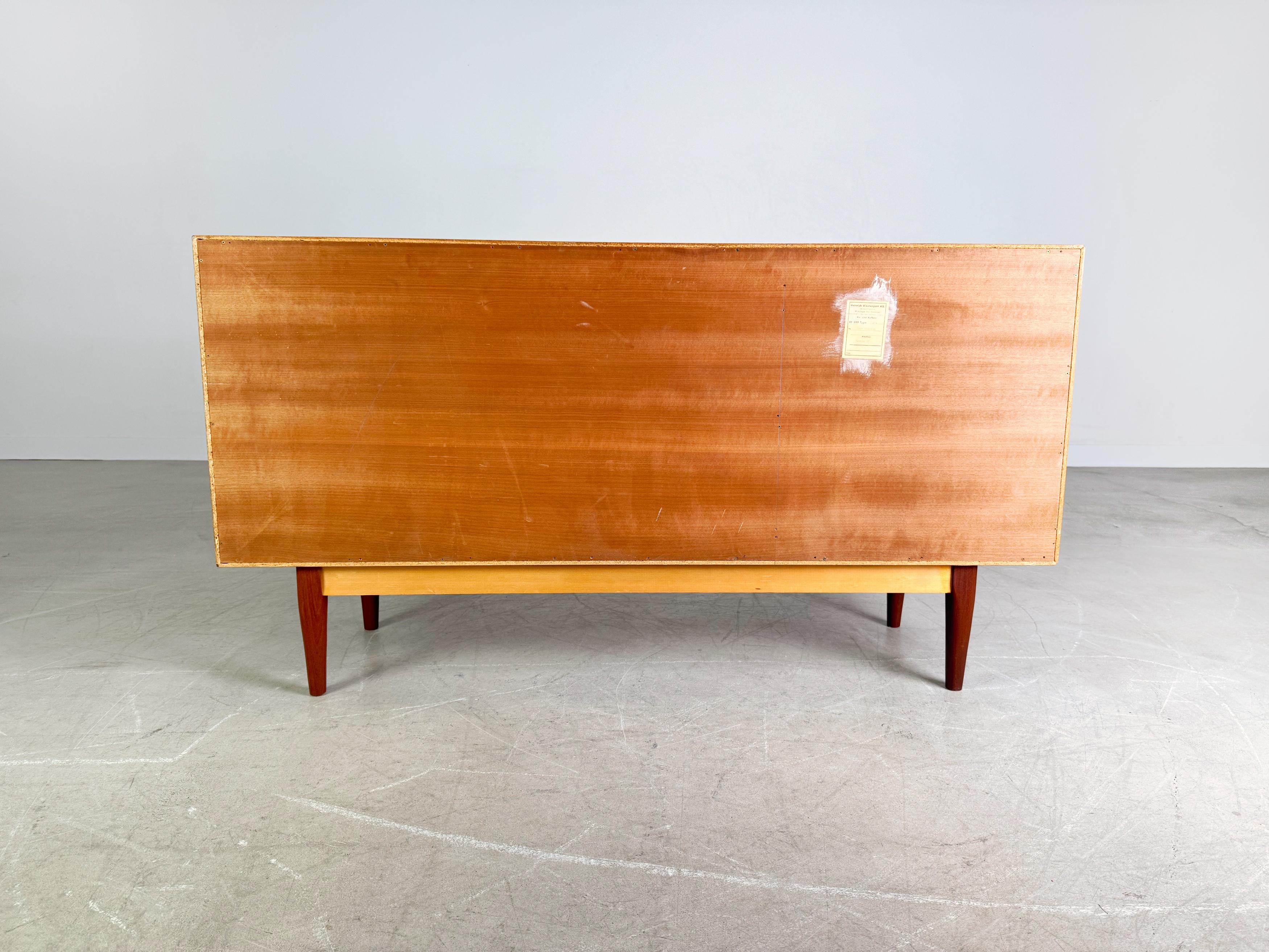 Wir bieten ein wunderschönes Vintage Teak Sideboard aus den 1960er Jahren zum Verkauf an. Das Design lehnt an die Entwürfe von Heinrich Riestenpatt an, besticht allerdings mit seiner praktischen Größe, die etwas kürzer ist. Es bietet mit insgesamt