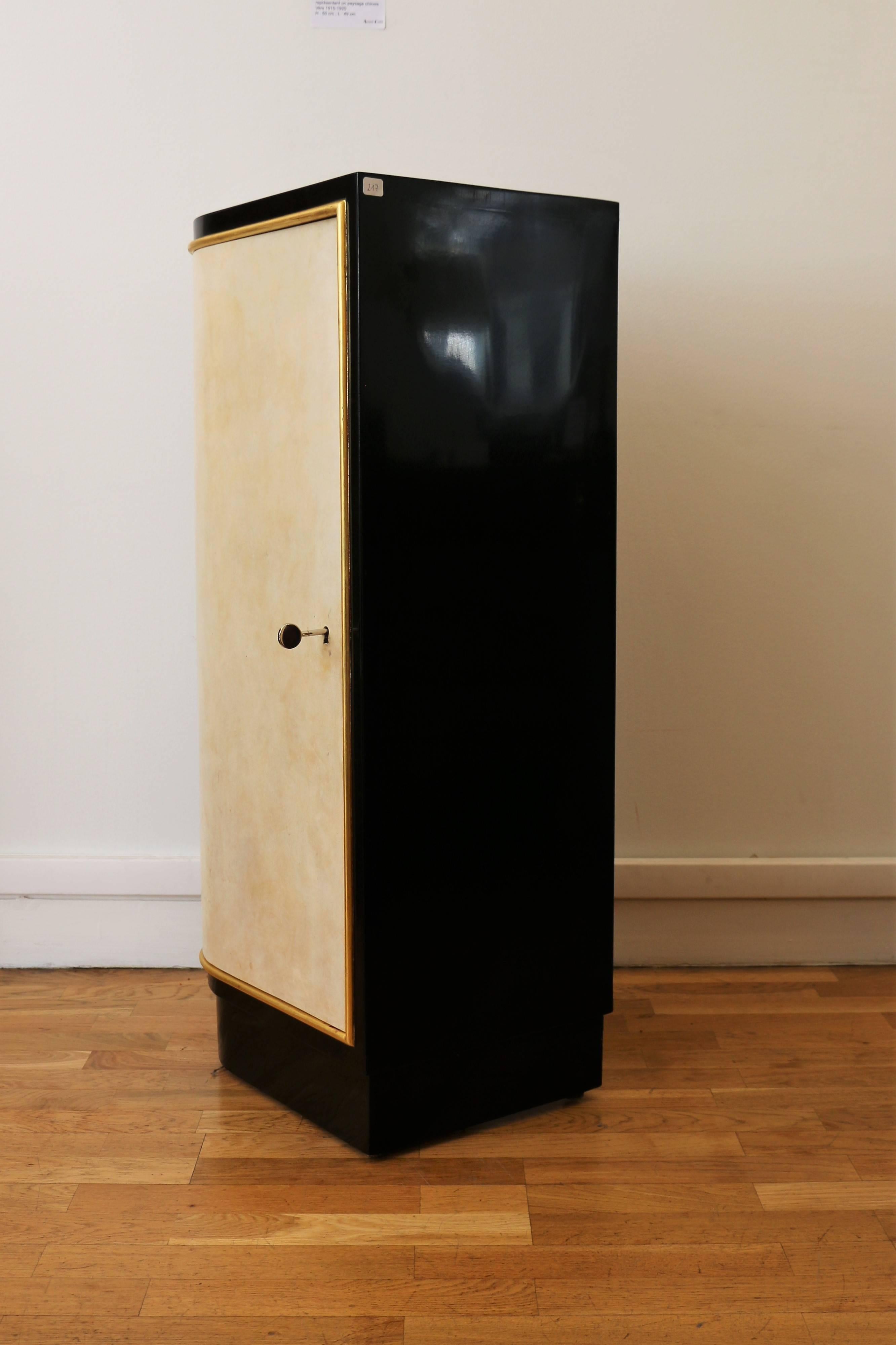 A bar cabinet in black lacquered wood by Maison Dominique. The door is covered with parchment with a gilded ring. Interior made of sycamore wood. Shelves and compartments for glasses and bottles.