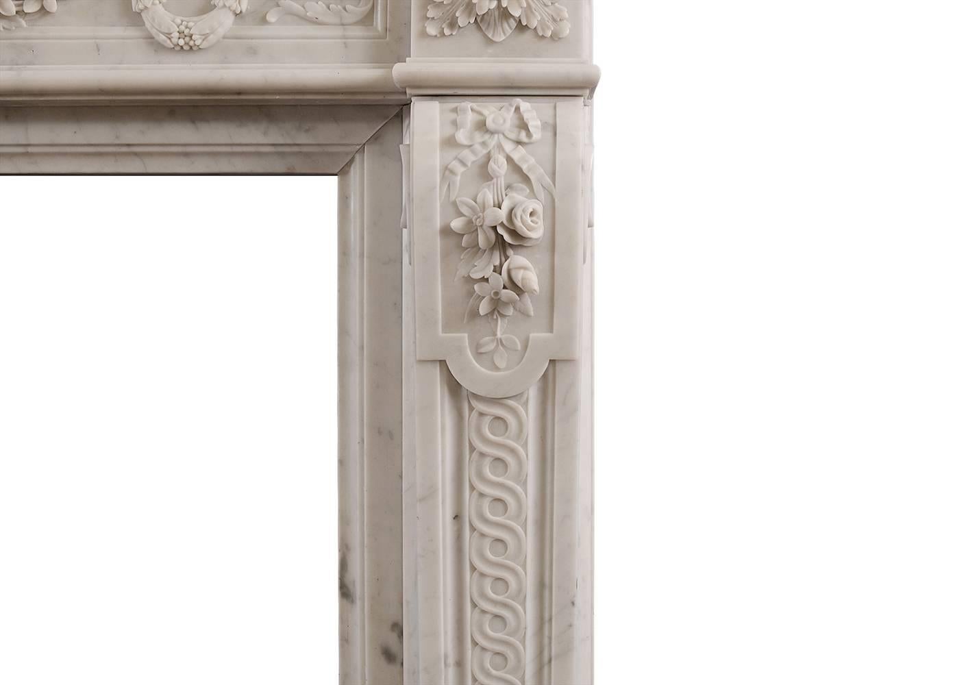Ein französischer Kamin aus Carrara-Marmor im Louis-XVI-Stil aus dem 19. Jahrhundert. Der getäfelte Fries mit Fackel und Köcher in der Mitte, geschnitzten Kränzen und drapierten Blumen. Die verschnörkelten Pfosten mit gebundenen Bändern und