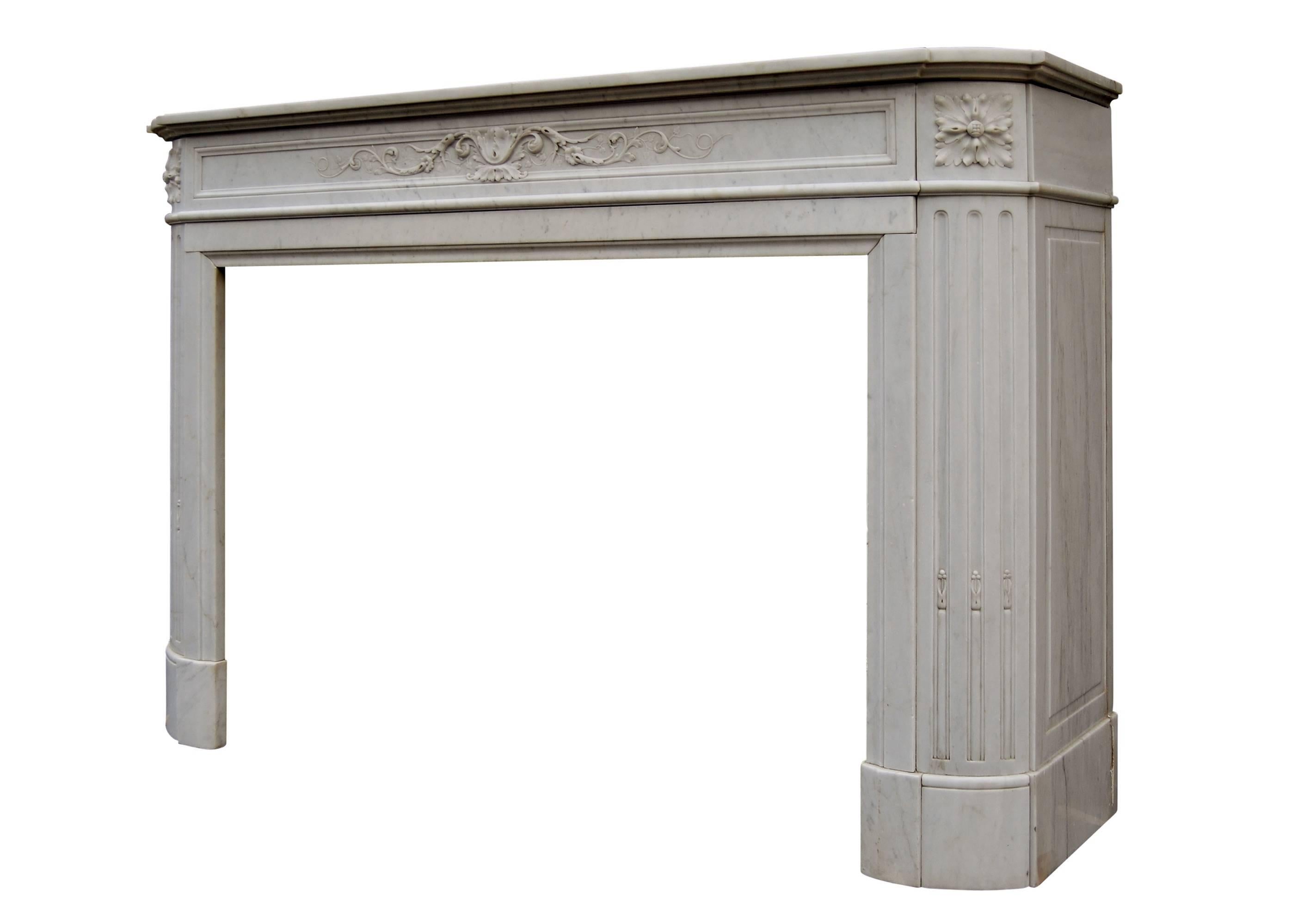 A 19th century French Louis XVI style Carrara marble fireplace with carved frieze of leaves and scrolls, demilune jambs with flutes surmounted by carved leaf paterae. Shaped shelf.

Measures: Shelf width - 1588 mm 62 ½ in
Overall height - 1092 mm